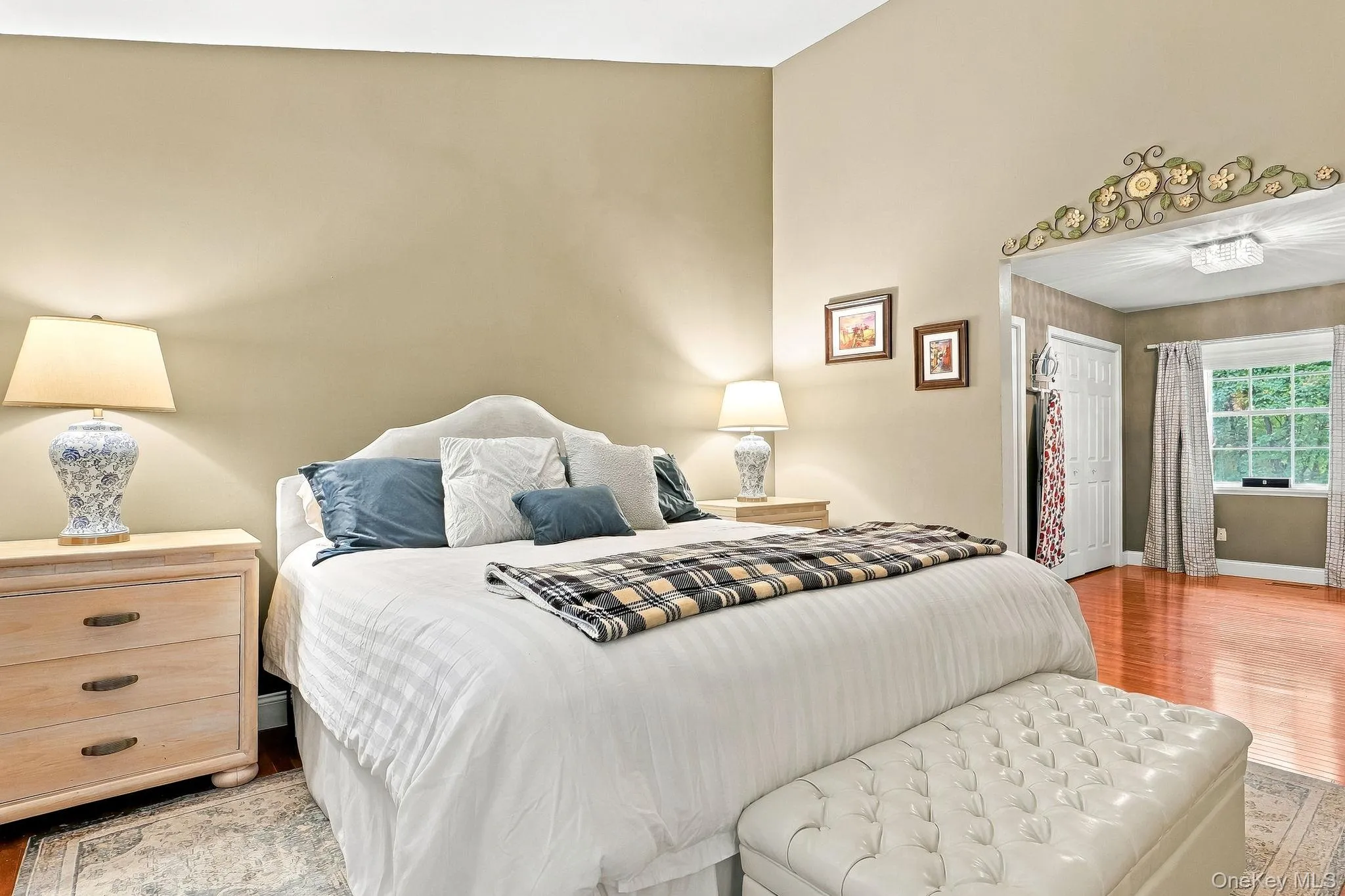 Vaulted ceiling with light-toned walls, rich wood-finish flooring, and a decorative archway Vaulted ceiling with light-toned walls, rich wood-finish flooring, and a decorative archway