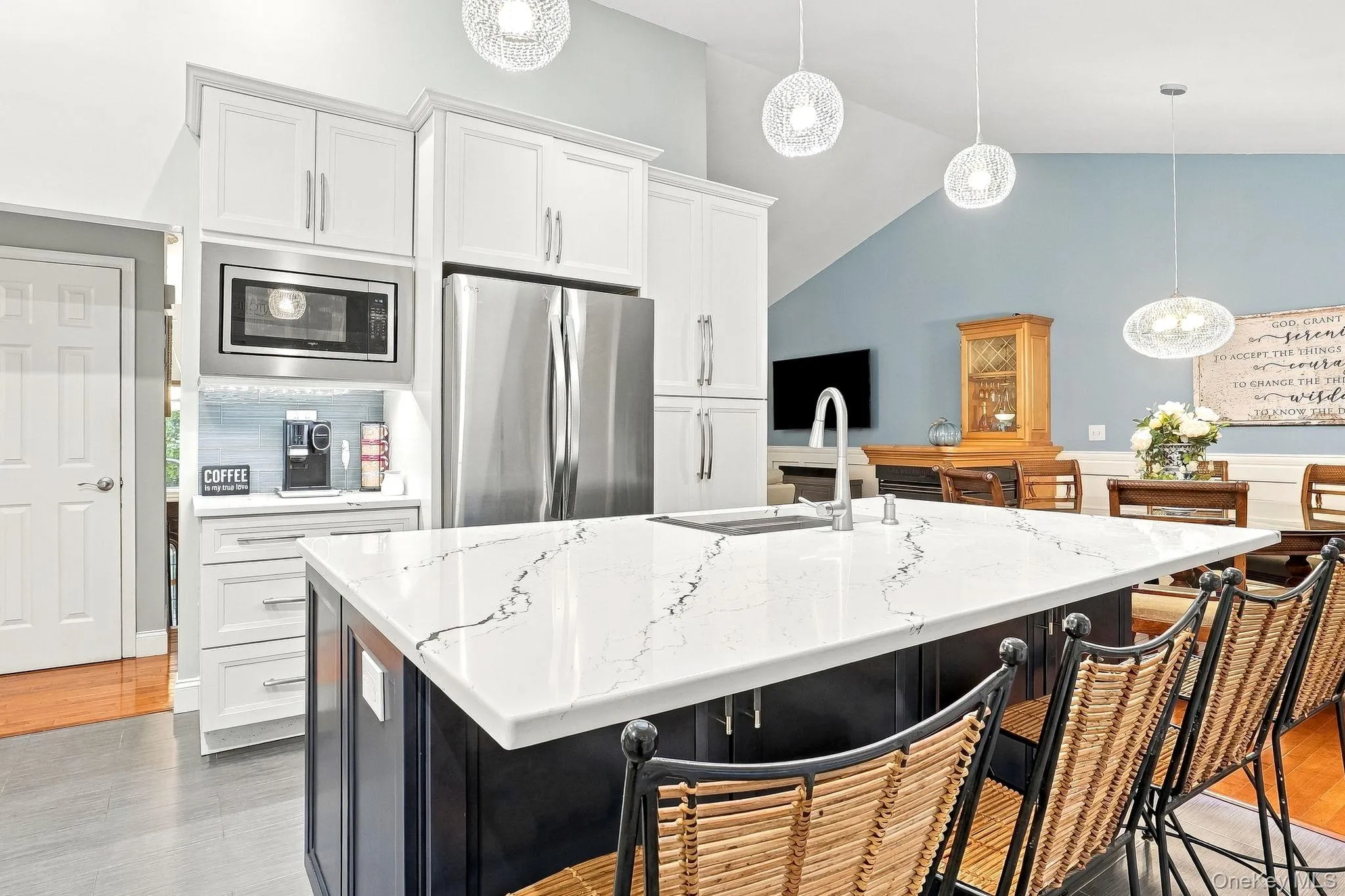 Kitchen featuring white cabinetry, stainless steel appliances, a large island with a countertop, and pendant lighting Kitchen featuring white cabinetry, stainless steel appliances, a large island with a countertop, and pendant lighting