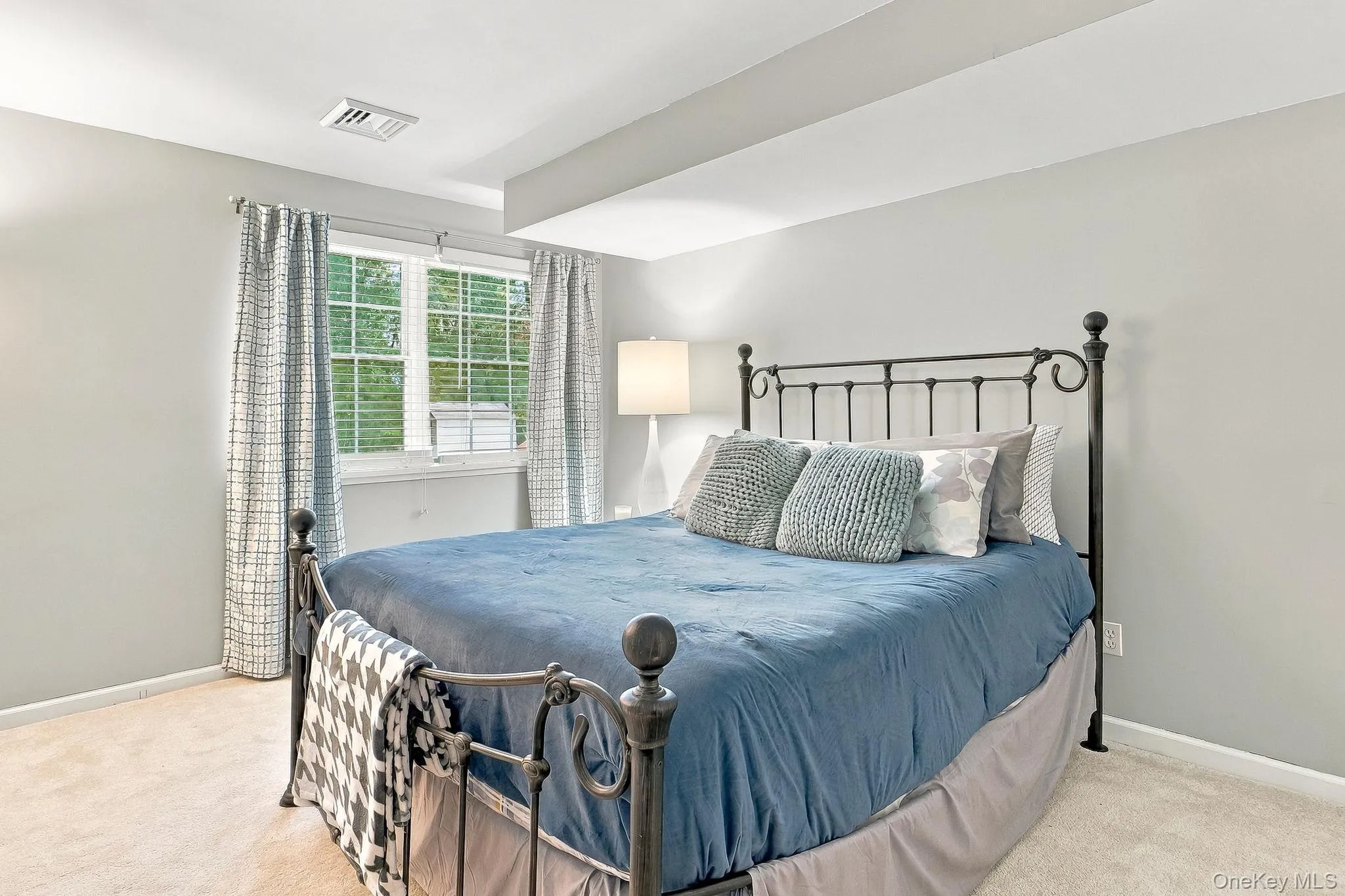 Carpeted room with light gray walls, a window featuring horizontal blinds, and a built-in recessed ceiling Carpeted room with light gray walls, a window featuring horizontal blinds, and a built-in recessed ceiling