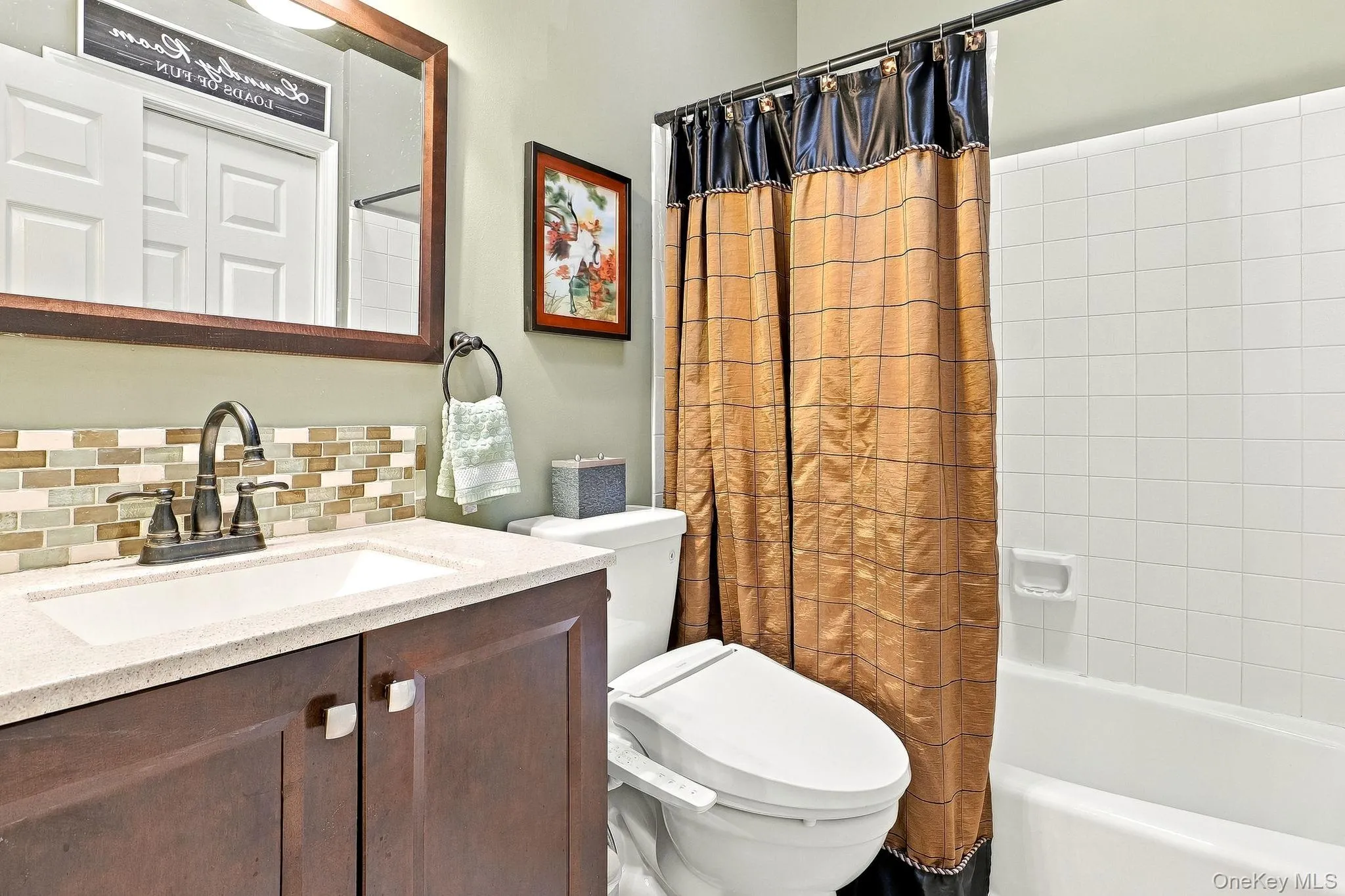 Vanity with a light-countertop, mosaic tile backsplash, and dark wood-finish cabinetry Vanity with a light-countertop, mosaic tile backsplash, and dark wood-finish cabinetry