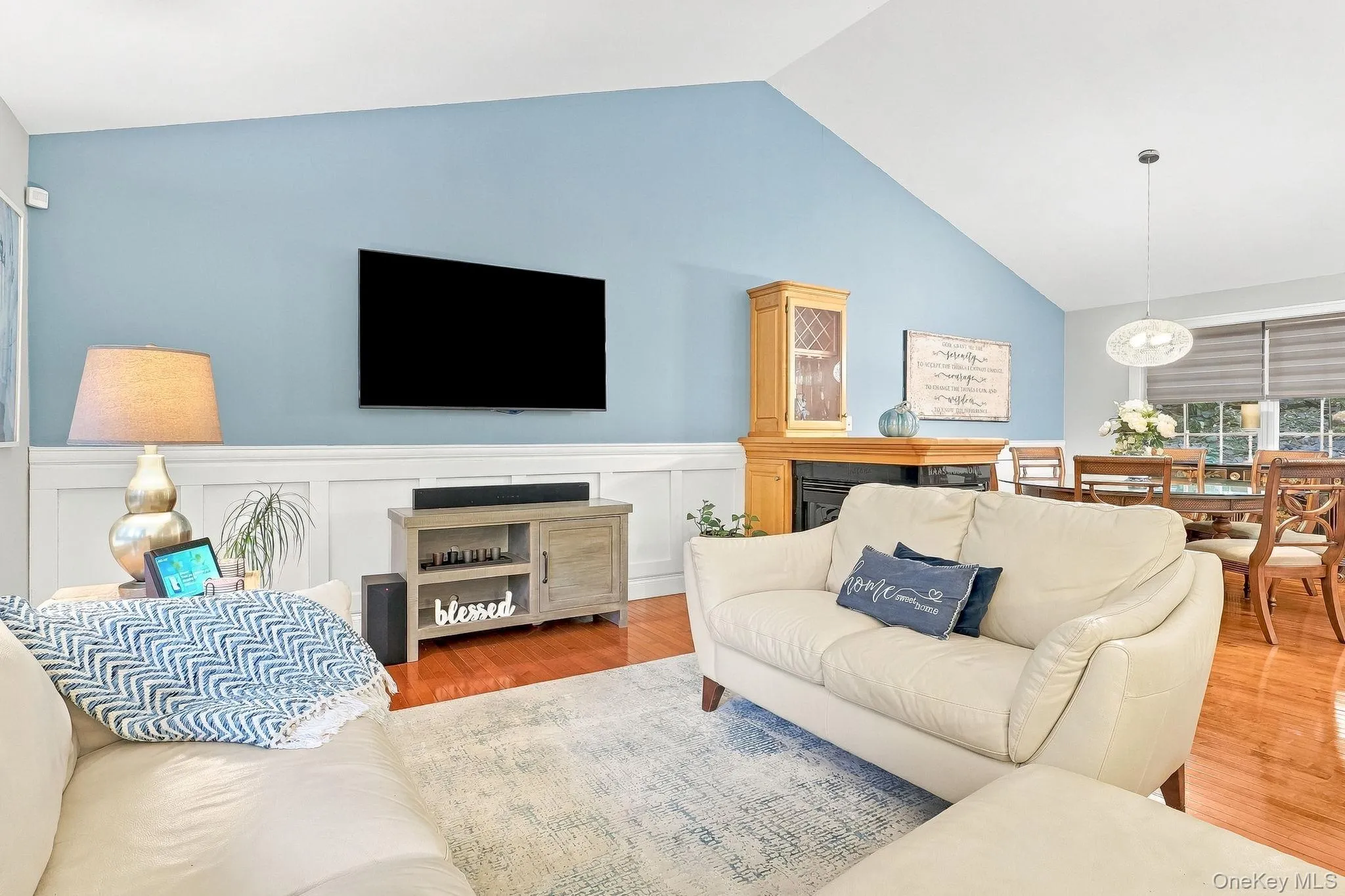 Vaulted ceiling, wood-flooring, wainscoting, fireplace with built-in cabinetry, and a modern dining pendant light Vaulted ceiling, wood-flooring, wainscoting, fireplace with built-in cabinetry, and a modern dining pendant light