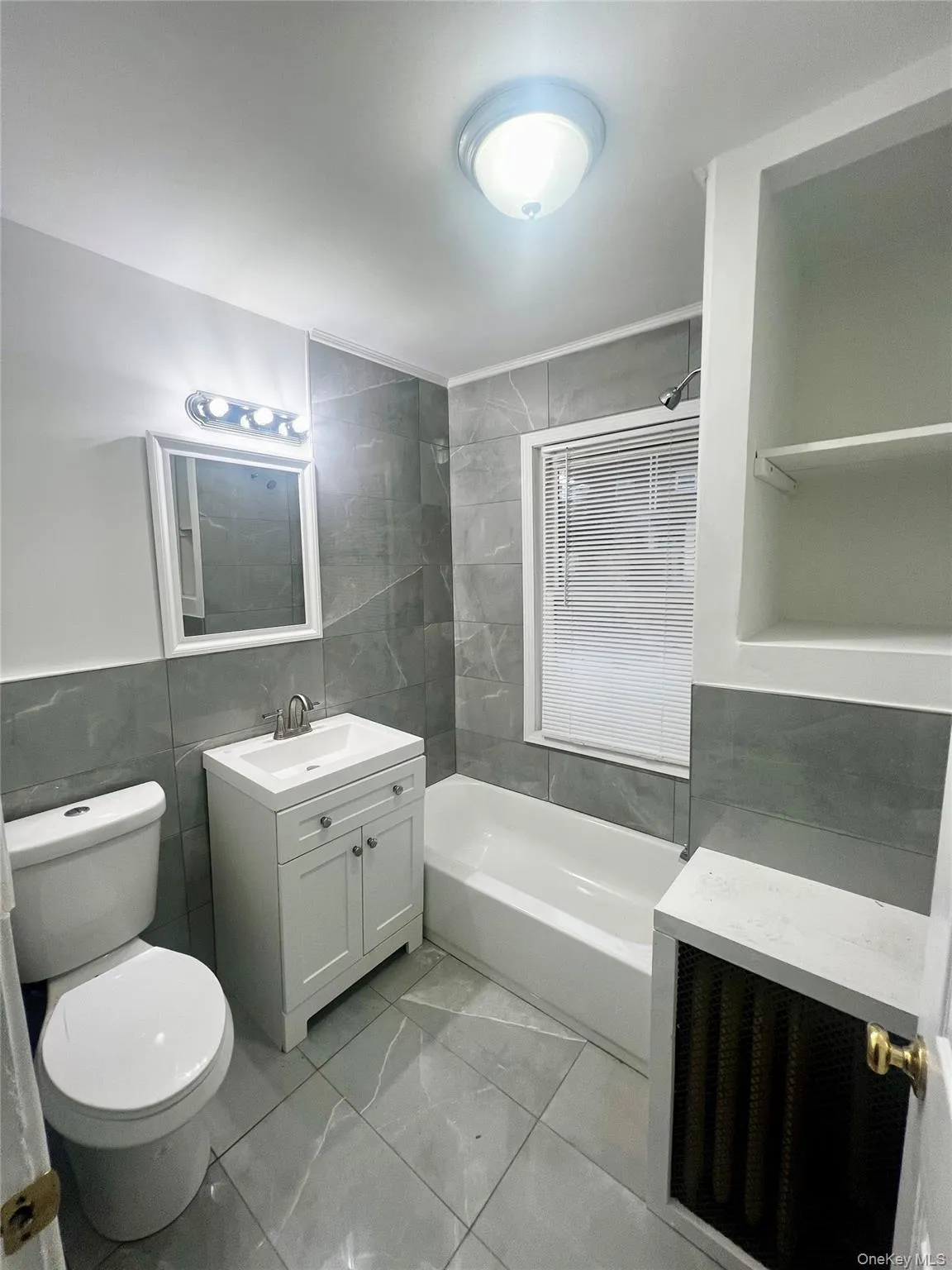 Full bathroom featuring tile walls, vanity, shower / bath combination, and wainscoting Full bathroom featuring tile walls, vanity, shower / bath combination, and wainscoting