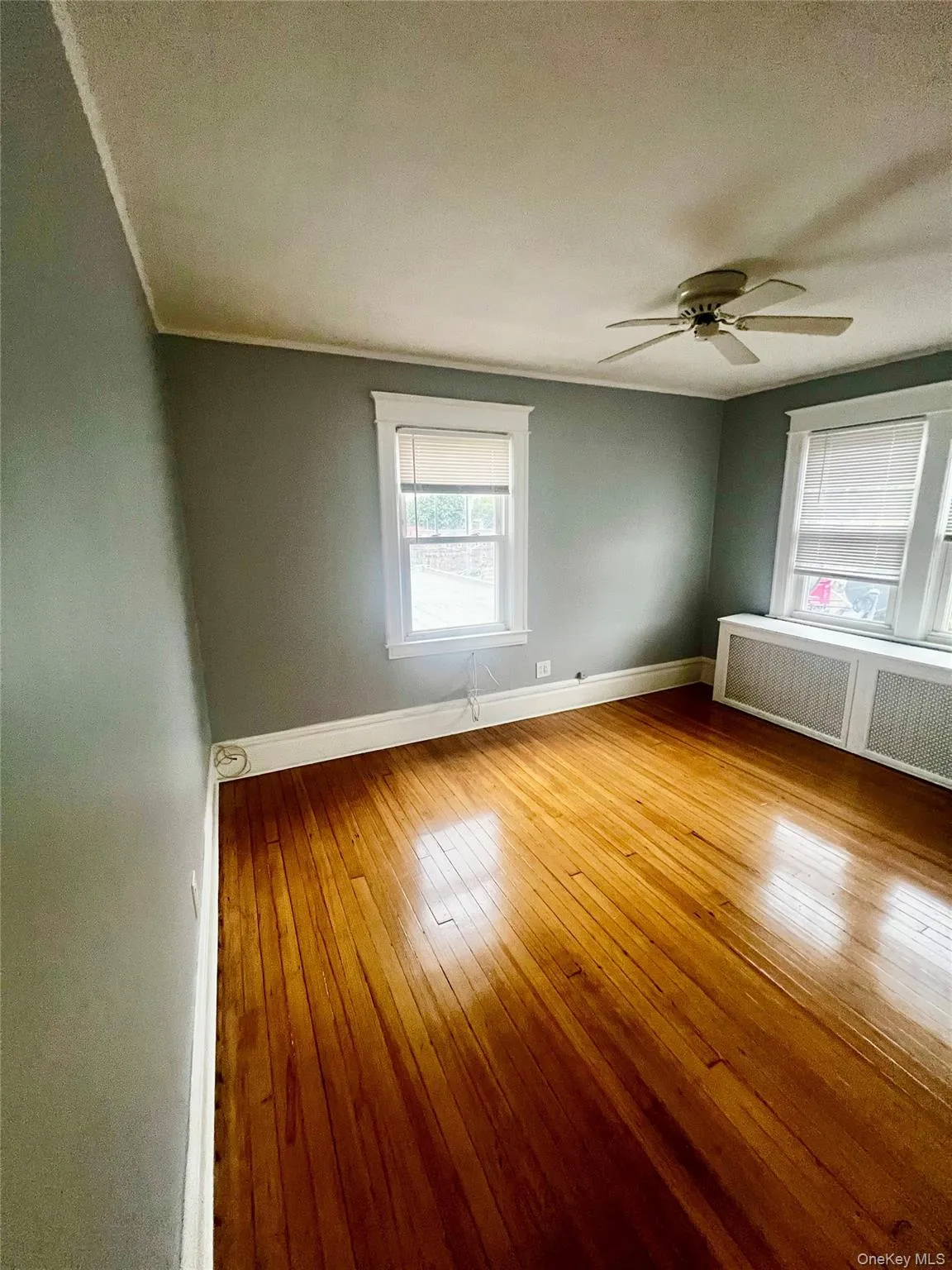 Unfurnished room with radiator, light wood-style floors, and ceiling fan Unfurnished room with radiator, light wood-style floors, and ceiling fan
