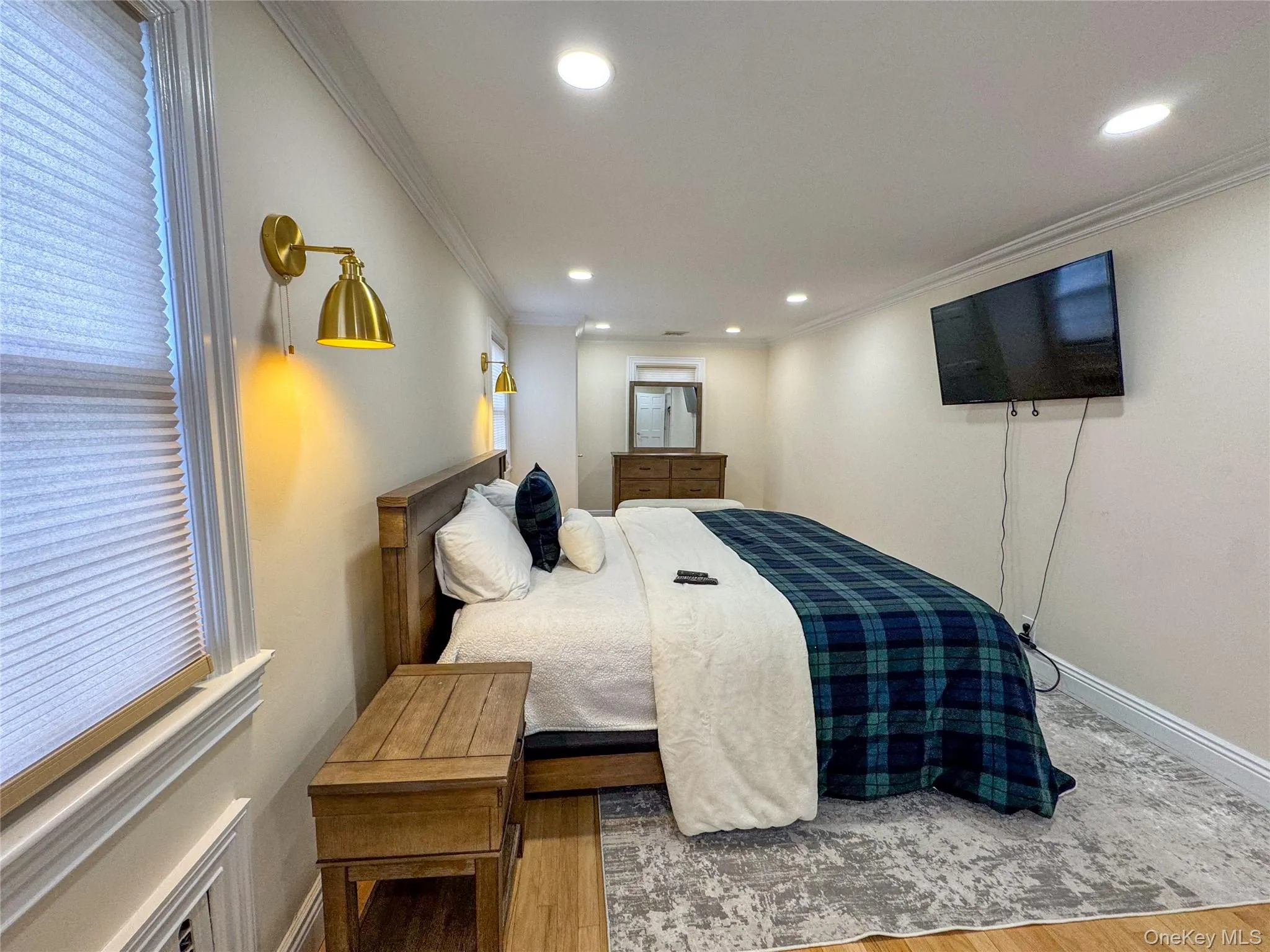 Wood-finish flooring with a decorative area rug, recessed ceiling lighting, and crown molding Wood-finish flooring with a decorative area rug, recessed ceiling lighting, and crown molding