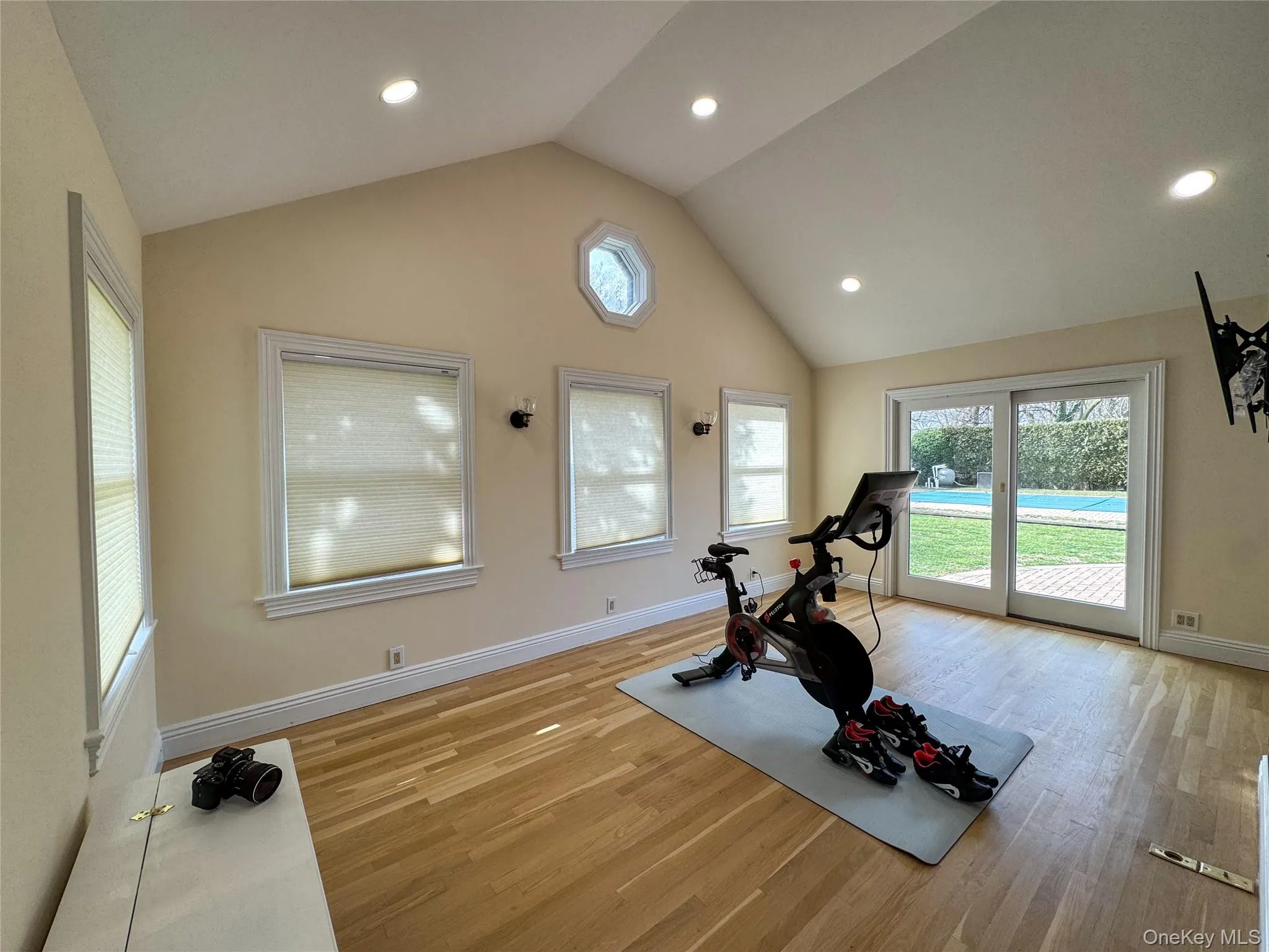 Vaulted ceiling with recessed lighting, wood-finish flooring, multiple windows, and sliding glass doors opening to the exterior Vaulted ceiling with recessed lighting, wood-finish flooring, multiple windows, and sliding glass doors opening to the exterior