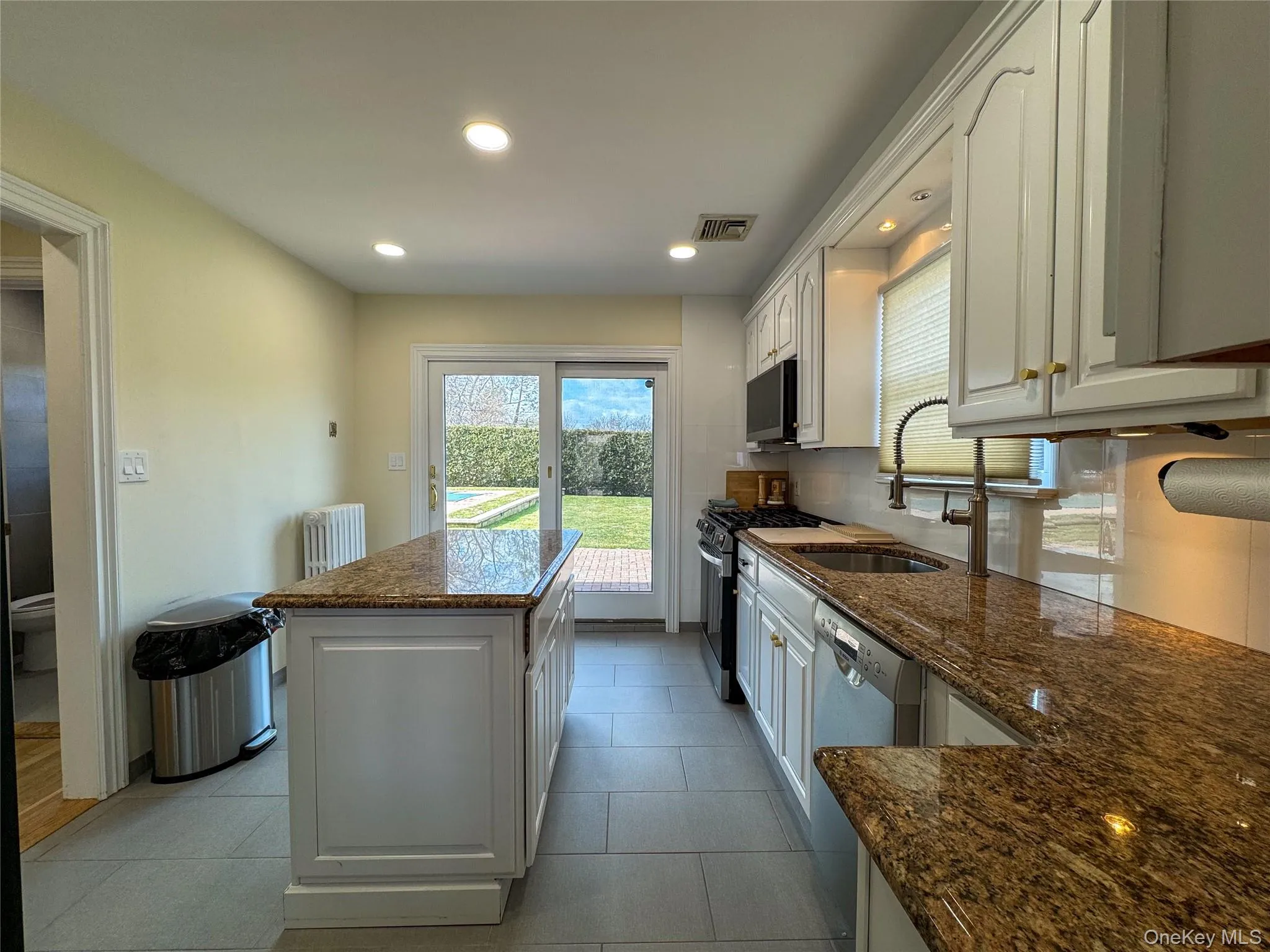 White cabinetry and a center island with a stone countertop White cabinetry and a center island with a stone countertop