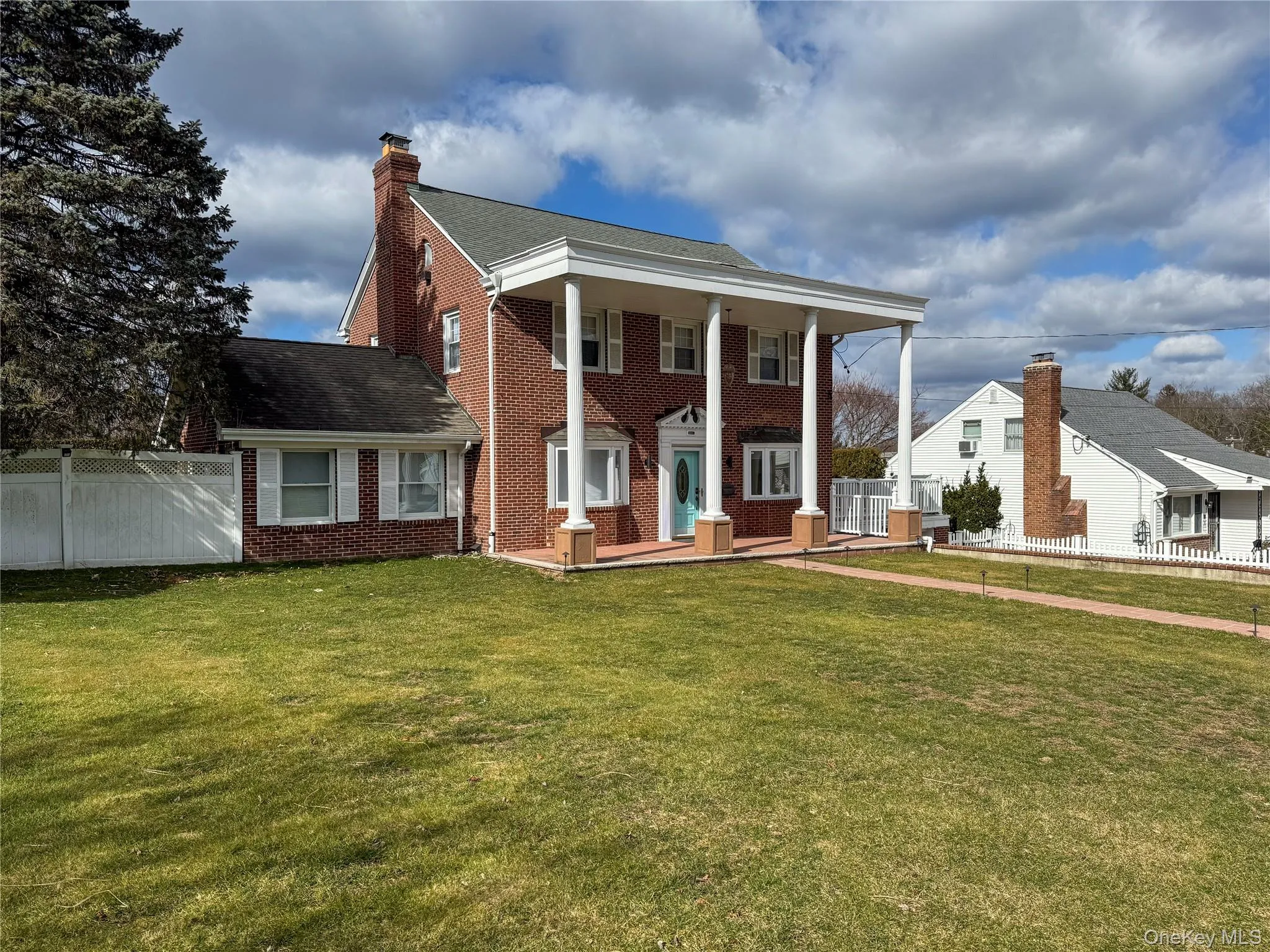 Brick exterior with white columned portico and turquoise entry door Brick exterior with white columned portico and turquoise entry door