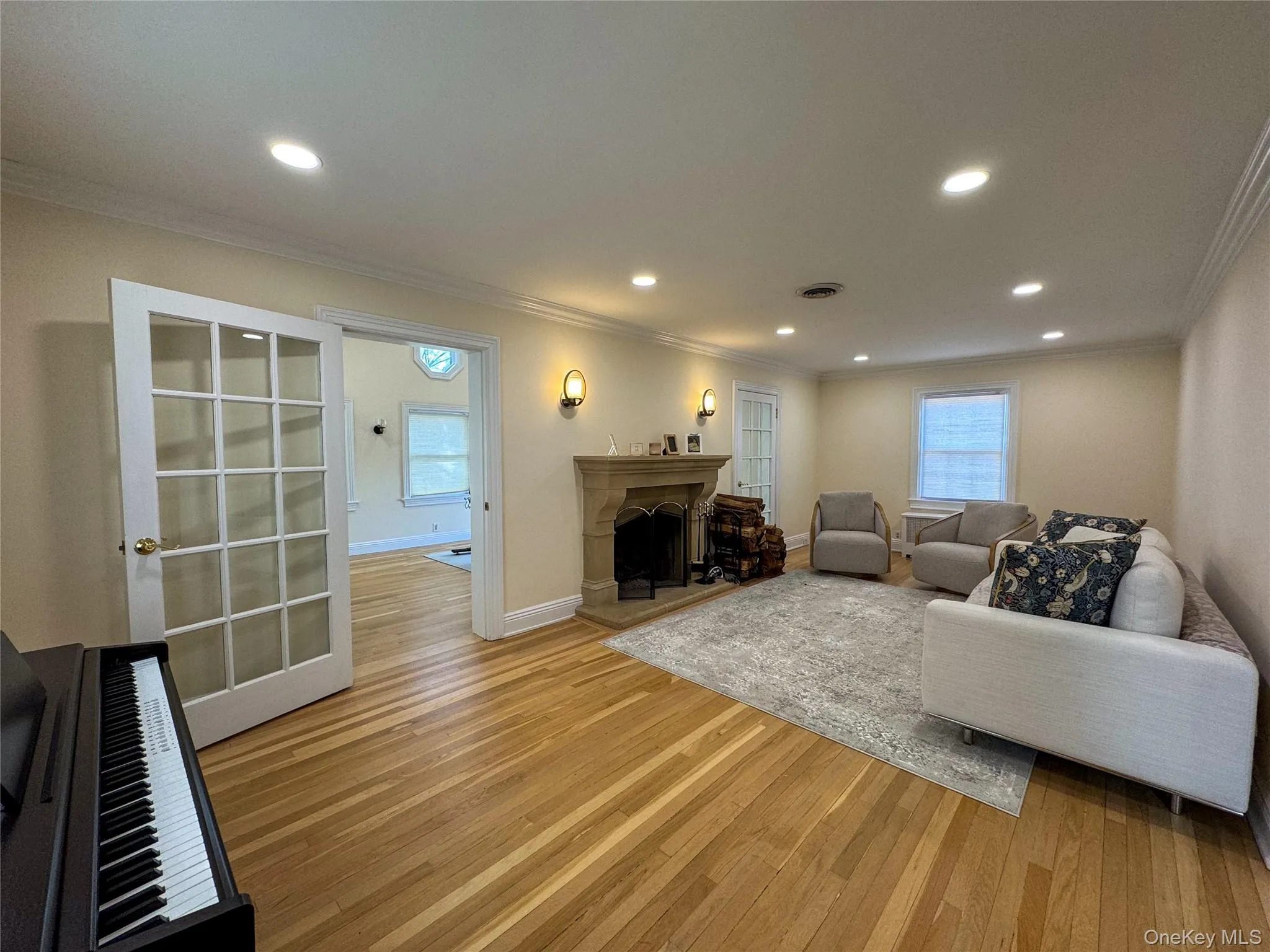 Hardwood flooring, recessed lighting, ornate fireplace with stone surround, crown molding, and French doors Hardwood flooring, recessed lighting, ornate fireplace with stone surround, crown molding, and French doors