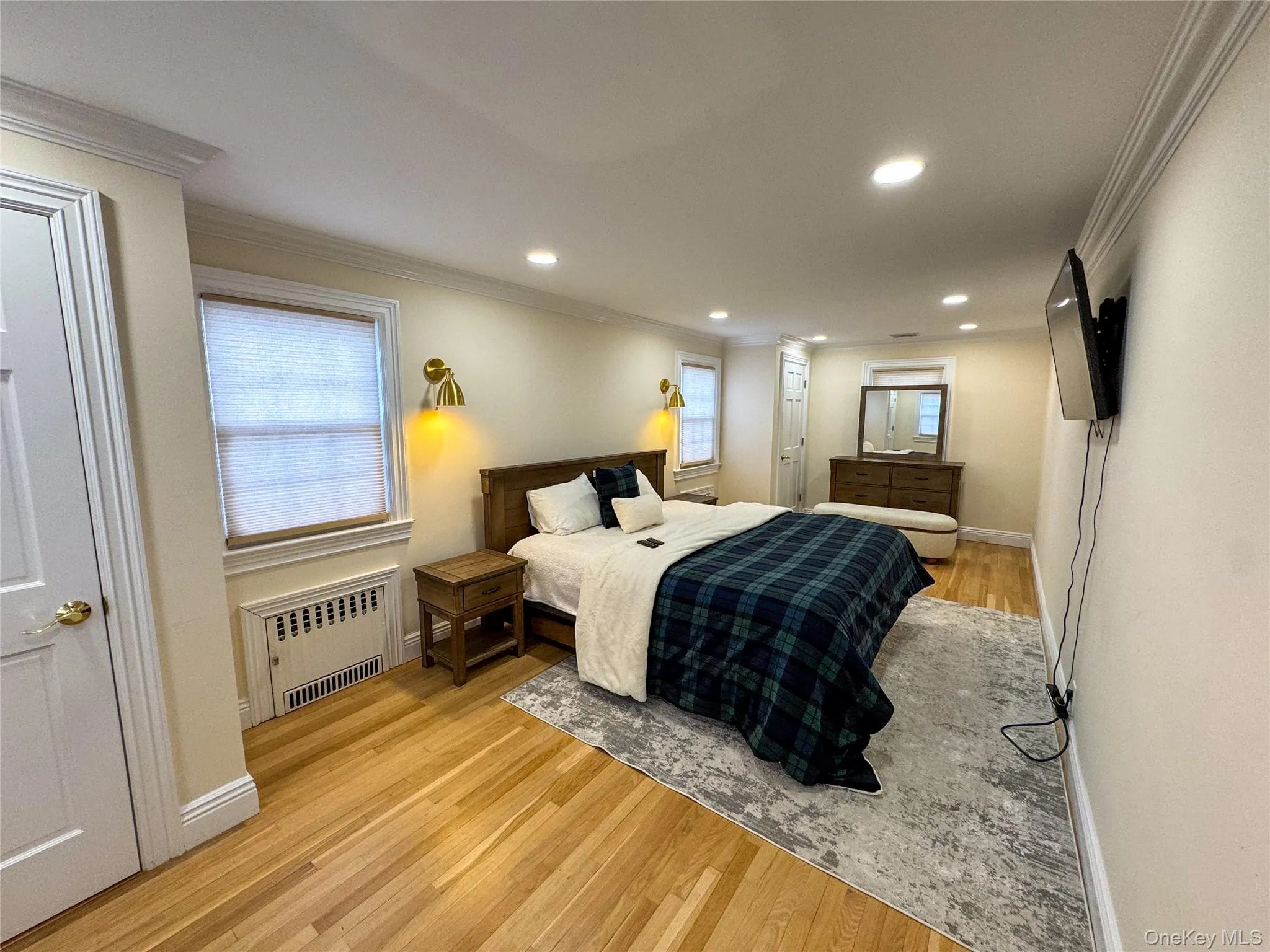 Hardwood flooring, recessed lighting, crown molding, wall-mounted light fixtures, and white paneled doors Hardwood flooring, recessed lighting, crown molding, wall-mounted light fixtures, and white paneled doors