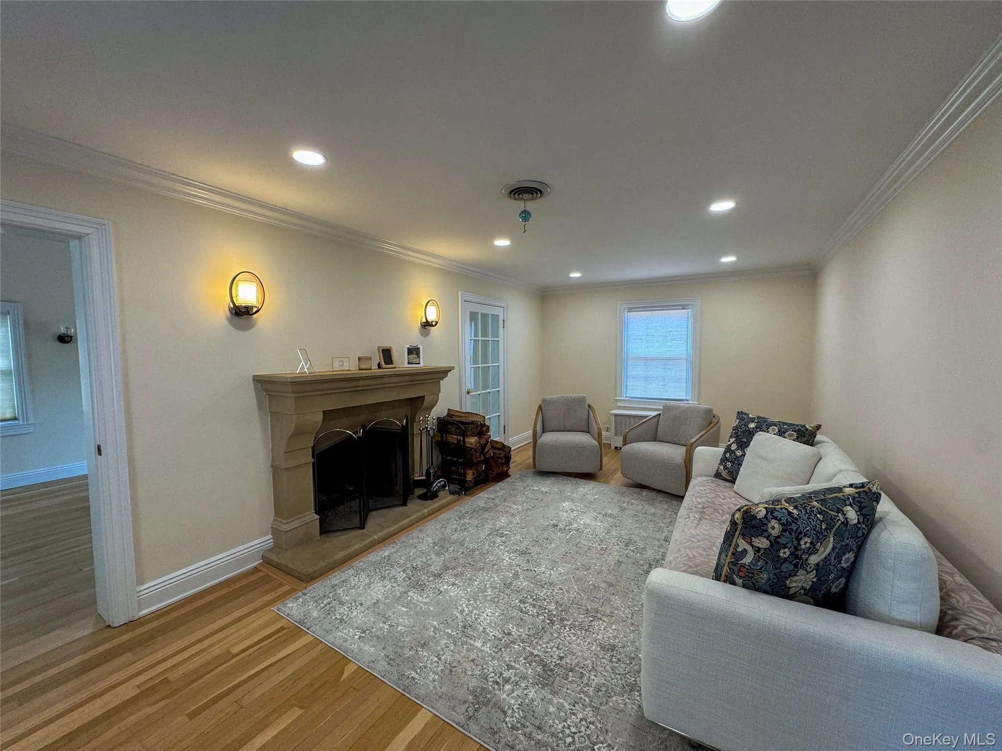 Recessed lighting, crown molding, wood-finish flooring, stone fireplace, and wall sconces Recessed lighting, crown molding, wood-finish flooring, stone fireplace, and wall sconces