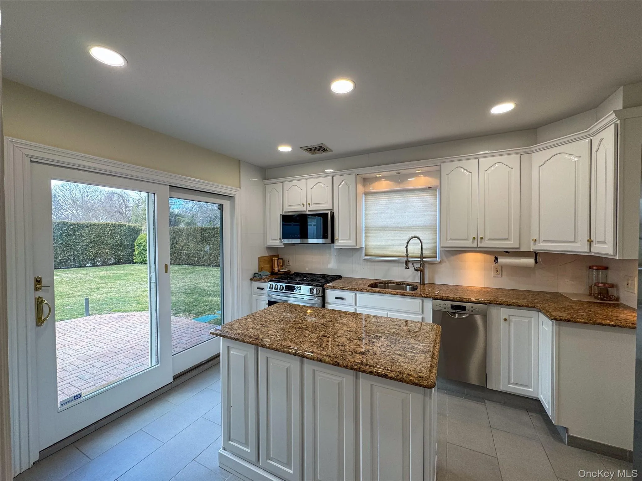 Kitchen featuring white cabinetry, granite countertops, stainless steel appliances, and tile flooring Kitchen featuring white cabinetry, granite countertops, stainless steel appliances, and tile flooring