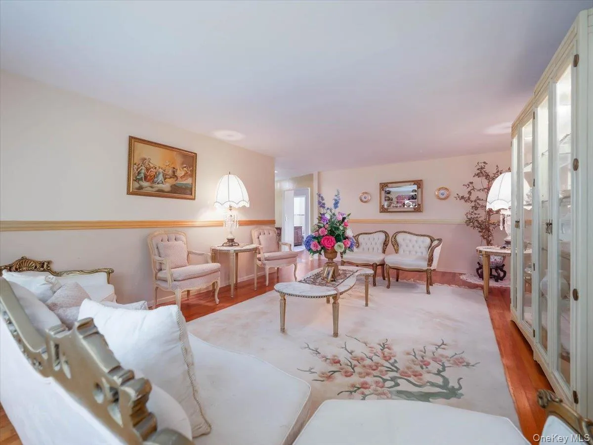 Interior room featuring hardwood flooring, chair rail molding, and a built-in floor-to-ceiling glass-front display cabinet Interior room featuring hardwood flooring, chair rail molding, and a built-in floor-to-ceiling glass-front display cabinet