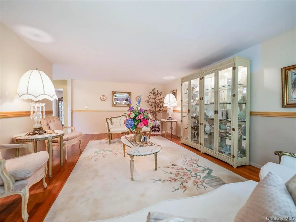 Living area featuring wood-finish flooring, custom built-in glass display cabinetry, and two-tone wall finish with chair rail molding Living area featuring wood-finish flooring, custom built-in glass display cabinetry, and two-tone wall finish with chair rail molding