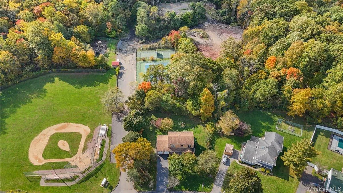Aerial perspective featuring expansive green space, mature deciduous trees, a baseball diamond, and a tennis court Aerial perspective featuring expansive green space, mature deciduous trees, a baseball diamond, and a tennis court