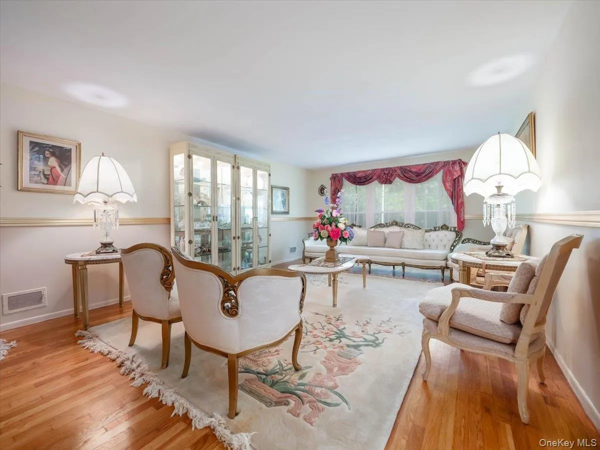Living space featuring wood-finish flooring, chair rail molding, and a built-in illuminated glass-front display cabinet Living space featuring wood-finish flooring, chair rail molding, and a built-in illuminated glass-front display cabinet