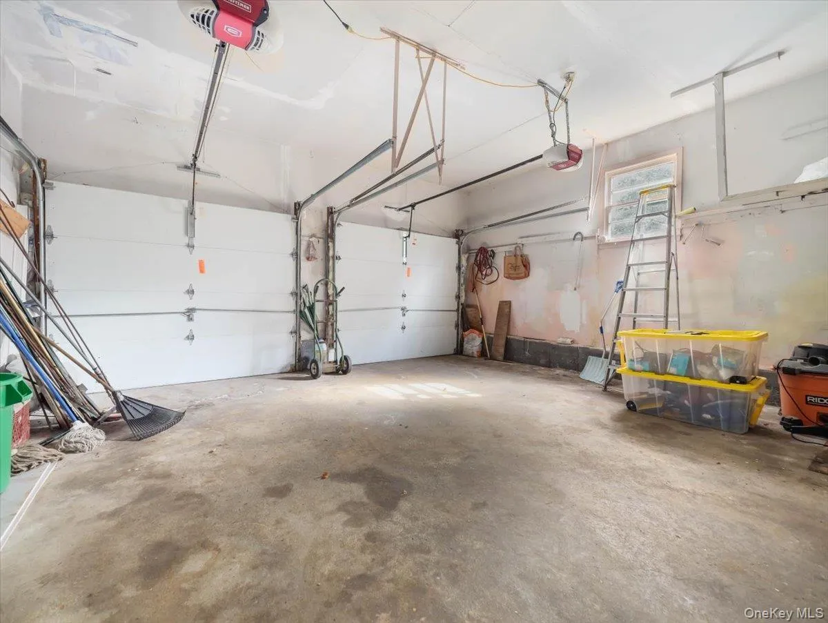 Two-car garage featuring dual overhead doors, concrete flooring, and a single window Two-car garage featuring dual overhead doors, concrete flooring, and a single window