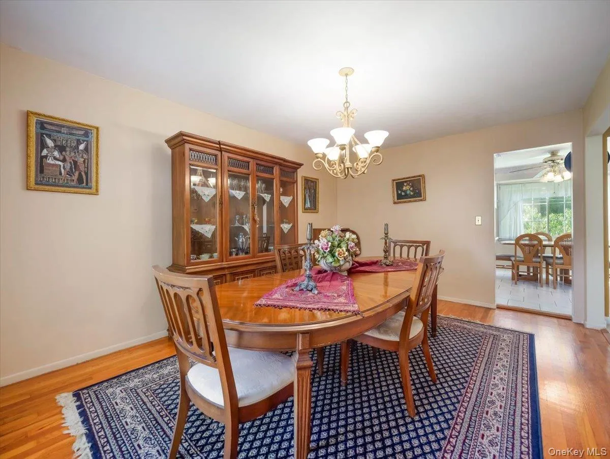Dining area featuring wood-finish flooring, a multi-arm brass chandelier, and built-in wood cabinetry Dining area featuring wood-finish flooring, a multi-arm brass chandelier, and built-in wood cabinetry
