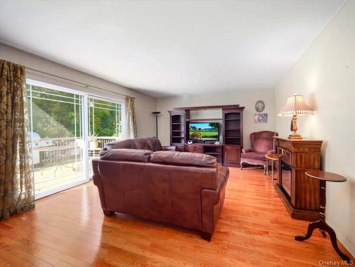 Living room featuring wood-finish flooring, a built-in media cabinet, and large glass sliding doors Living room featuring wood-finish flooring, a built-in media cabinet, and large glass sliding doors