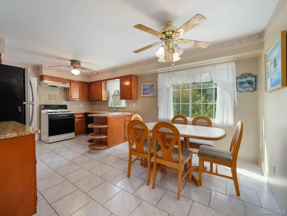 Kitchen featuring wood cabinetry, stone-finish countertops, tile flooring, and integrated ceiling fans with light fixtures Kitchen featuring wood cabinetry, stone-finish countertops, tile flooring, and integrated ceiling fans with light fixtures