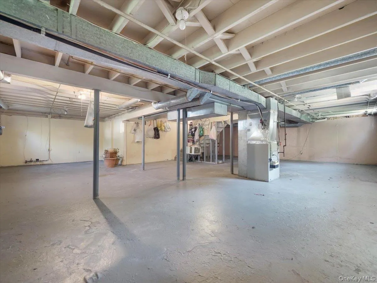 Unfinished basement featuring exposed structural ceiling joists, painted concrete flooring, and metal support columns Unfinished basement featuring exposed structural ceiling joists, painted concrete flooring, and metal support columns