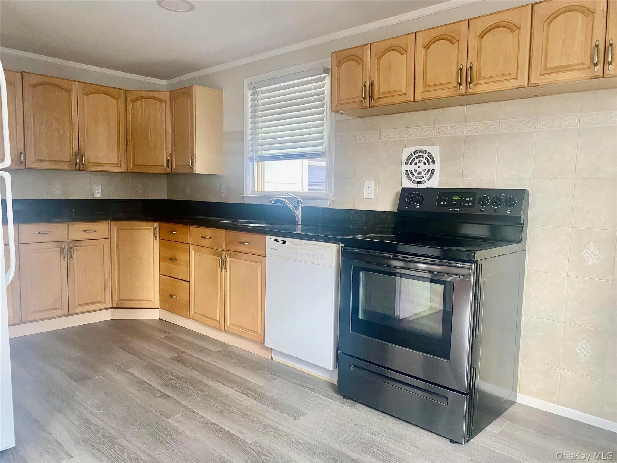 Cabinetry with arched panel doors, dark countertops, tile backsplash, stainless steel sink, and wood-finish flooring Cabinetry with arched panel doors, dark countertops, tile backsplash, stainless steel sink, and wood-finish flooring
