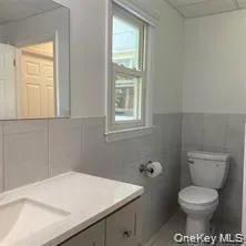 White two-panel door, rectangular window, white toilet, vanity with integrated sink and light-colored countertop, and a wall-mounted mirror White two-panel door, rectangular window, white toilet, vanity with integrated sink and light-colored countertop, and a wall-mounted mirror