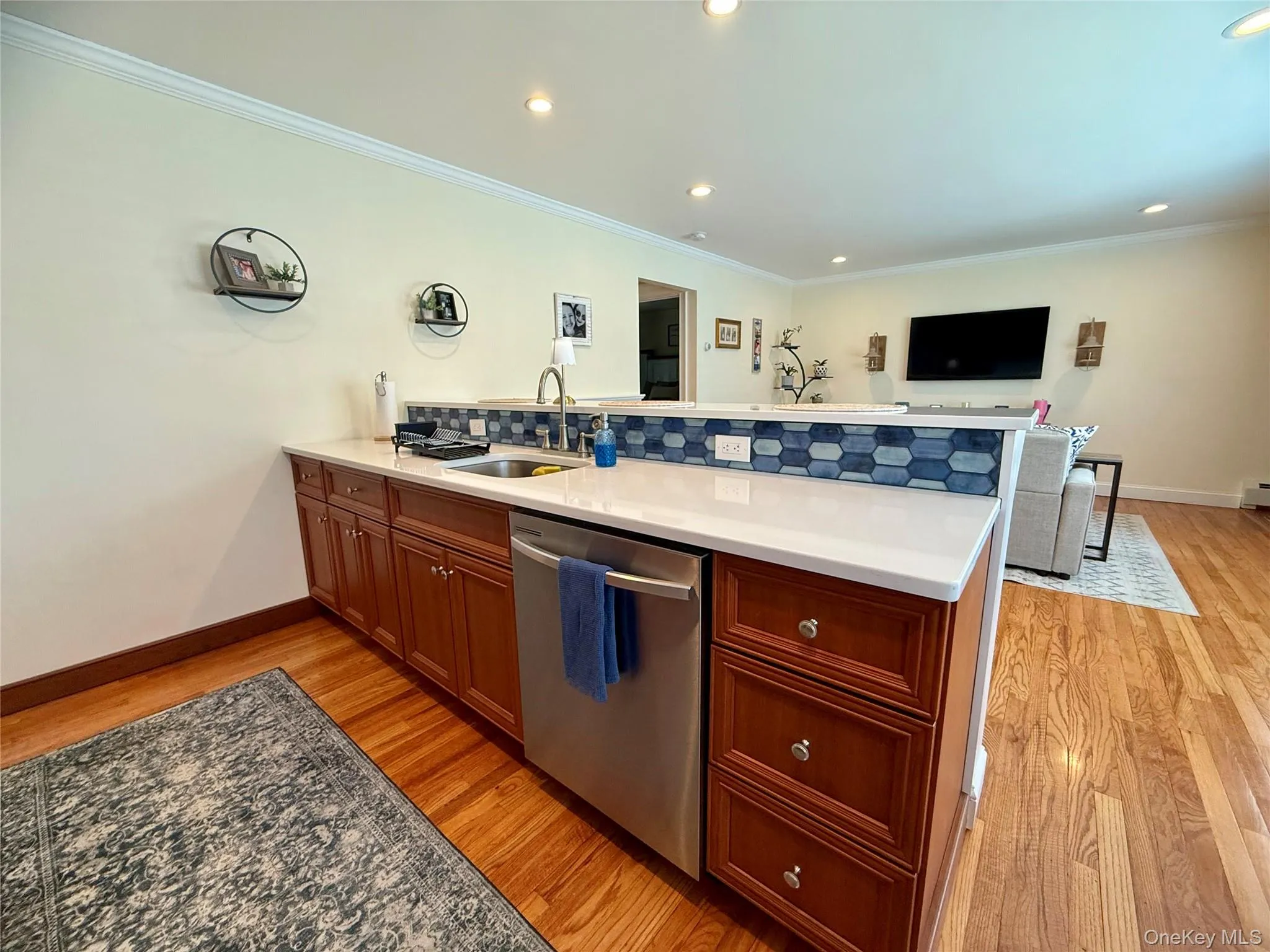 Kitchen with dishwasher, a peninsula, light wood finished floors, decorative backsplash, and crown molding Kitchen with dishwasher, a peninsula, light wood finished floors, decorative backsplash, and crown molding