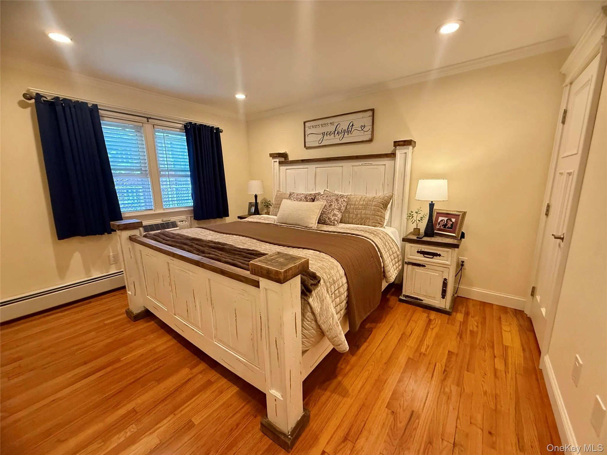 Bedroom with light wood finished floors, ornamental molding, recessed lighting, and baseboard heating Bedroom with light wood finished floors, ornamental molding, recessed lighting, and baseboard heating