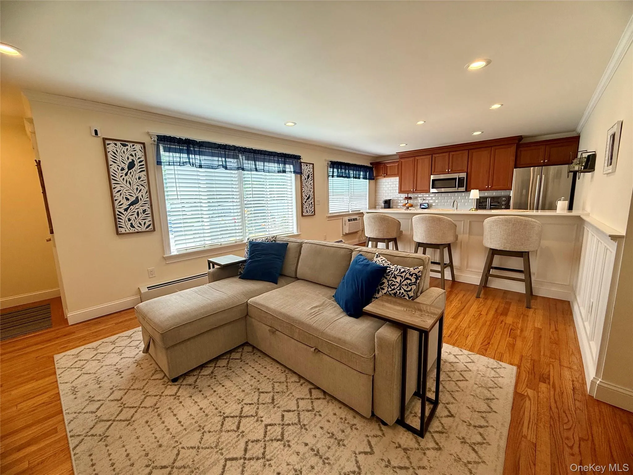 Living room with a baseboard heating unit, crown molding, light wood finished floors, and recessed lighting Living room with a baseboard heating unit, crown molding, light wood finished floors, and recessed lighting