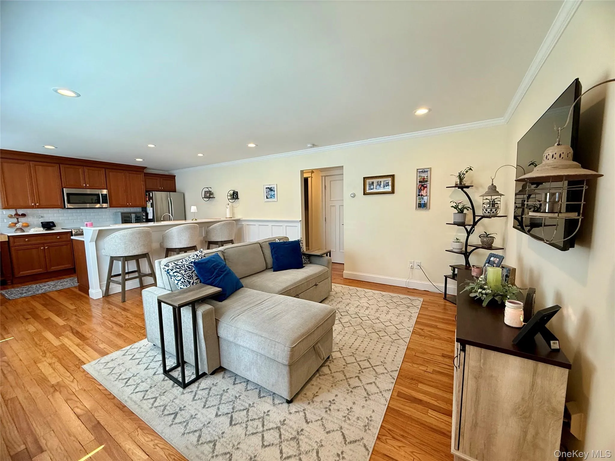 Living area with light wood-style flooring, ornamental molding, and recessed lighting Living area with light wood-style flooring, ornamental molding, and recessed lighting