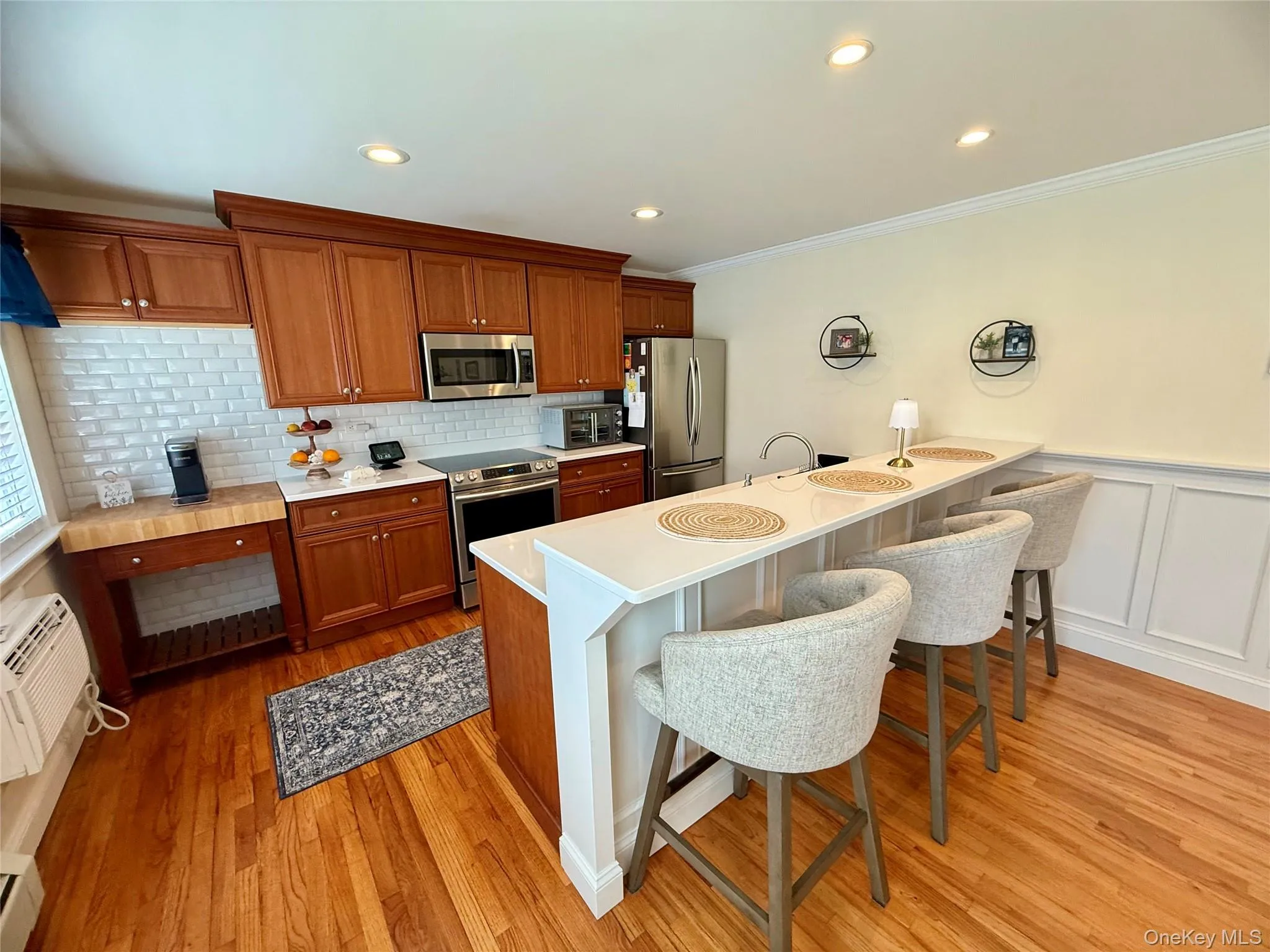 Kitchen featuring appliances with stainless steel finishes, a kitchen bar, crown molding, and light wood-type flooring Kitchen featuring appliances with stainless steel finishes, a kitchen bar, crown molding, and light wood-type flooring