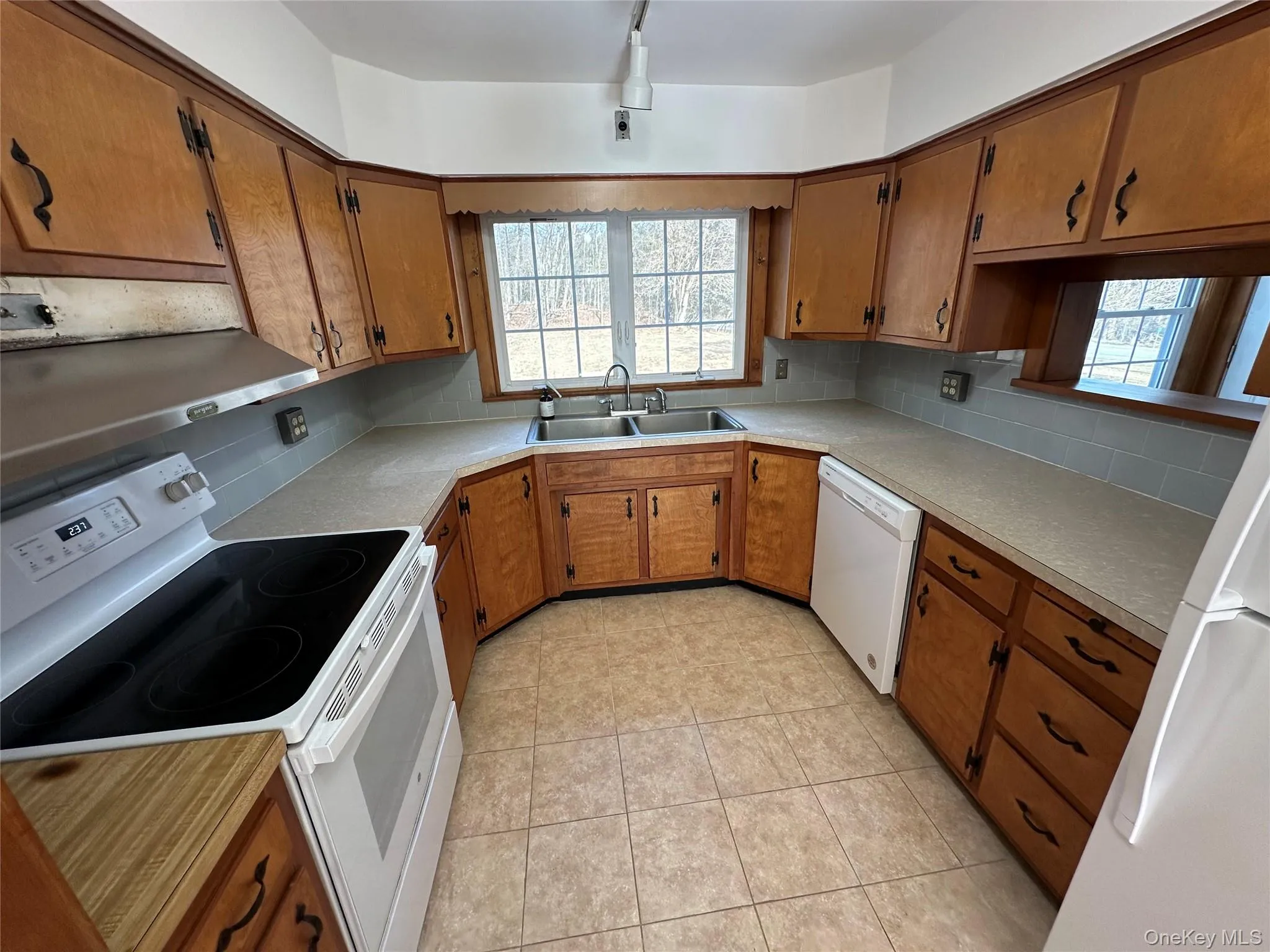 Kitchen with white appliances, decorative backsplash, a sink, and brown cabinets Kitchen with white appliances, decorative backsplash, a sink, and brown cabinets