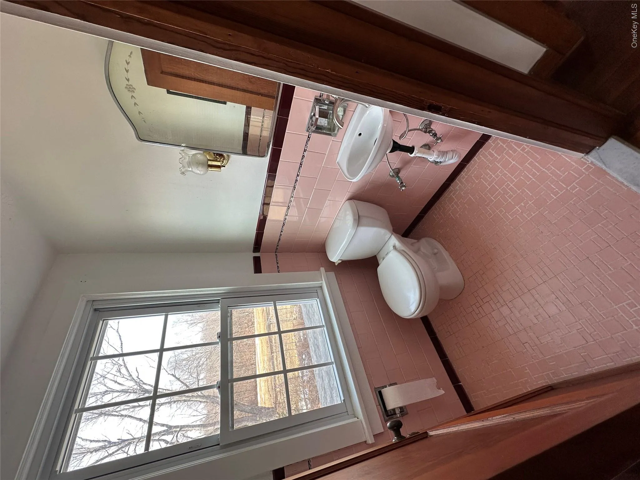 Bathroom with tile patterned flooring, toilet, a wainscoted wall, a sink, and tile walls Bathroom with tile patterned flooring, toilet, a wainscoted wall, a sink, and tile walls