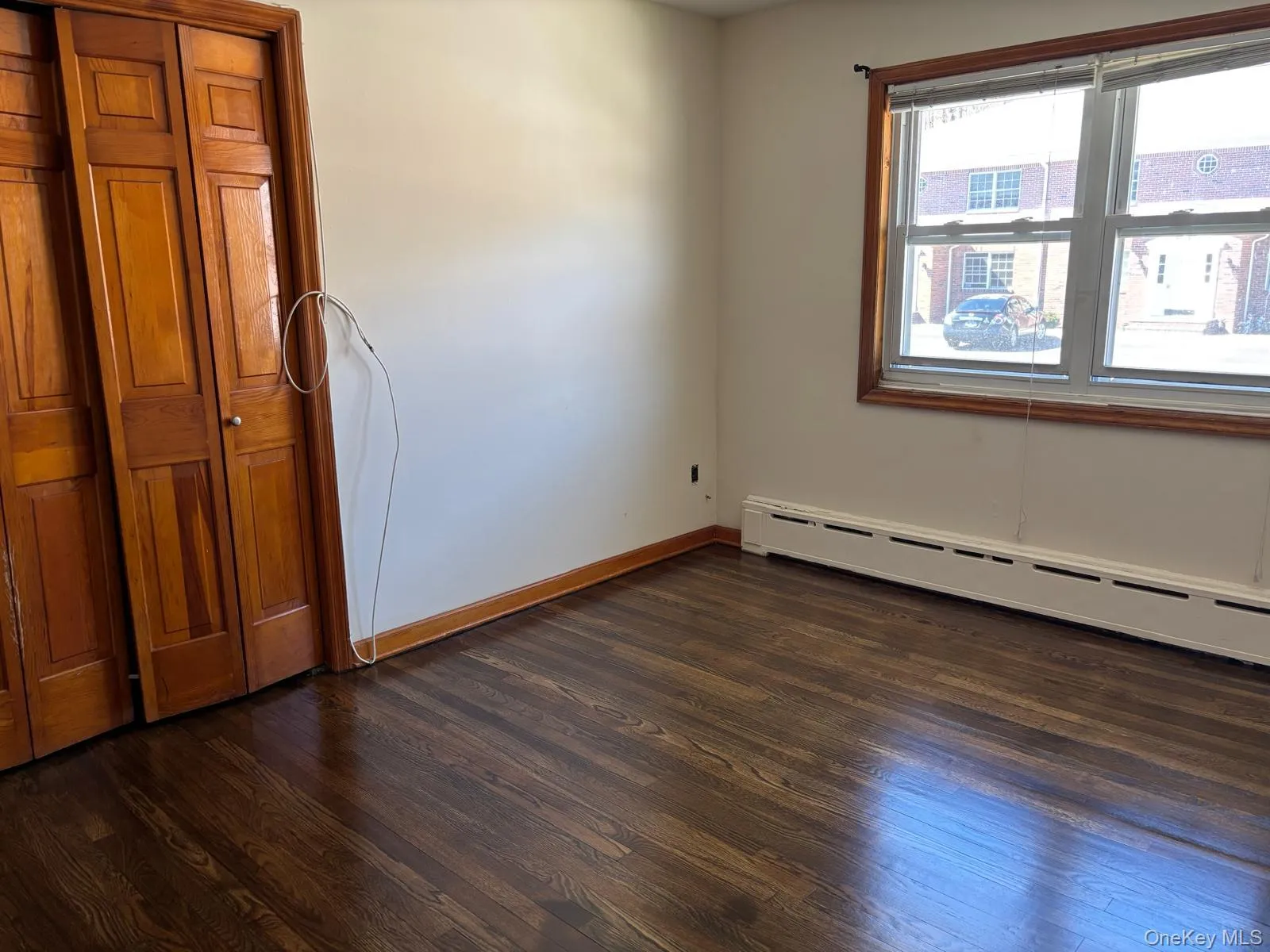 Spare room featuring dark wood-type flooring and a baseboard radiator Spare room featuring dark wood-type flooring and a baseboard radiator