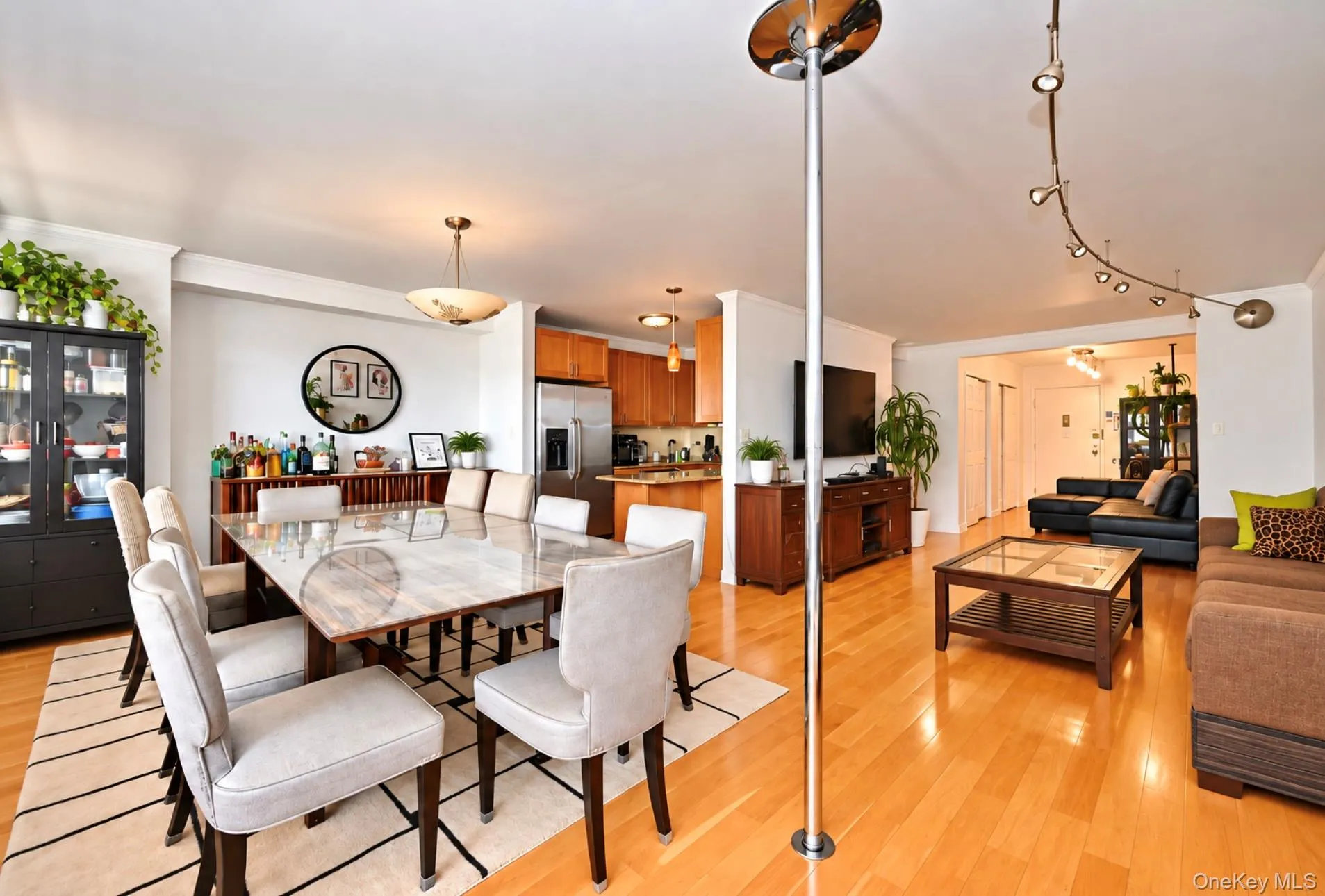 Open-concept living space with wood-finish flooring, recessed lighting, and a kitchen featuring wood cabinetry and stainless steel appliances Open-concept living space with wood-finish flooring, recessed lighting, and a kitchen featuring wood cabinetry and stainless steel appliances