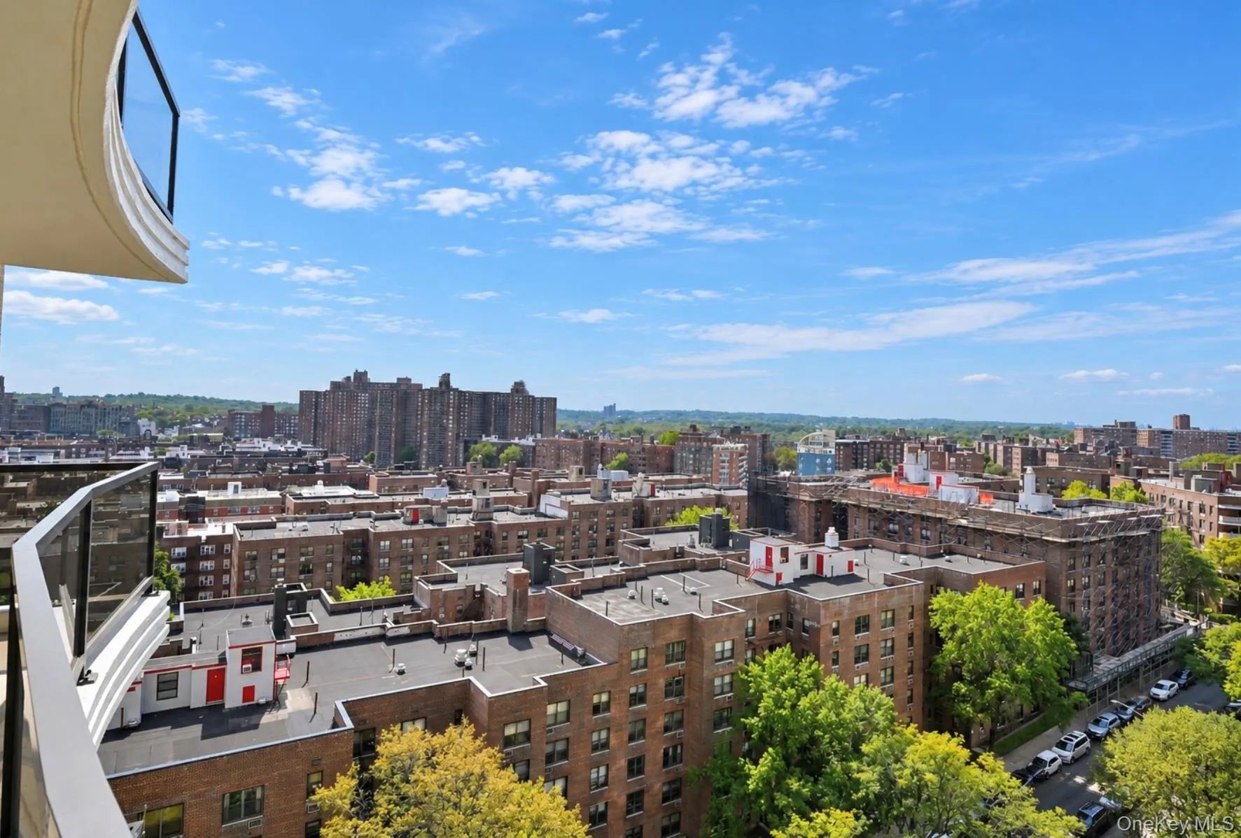 Curved balcony with glass railing, urban scenery, and distant structures Curved balcony with glass railing, urban scenery, and distant structures