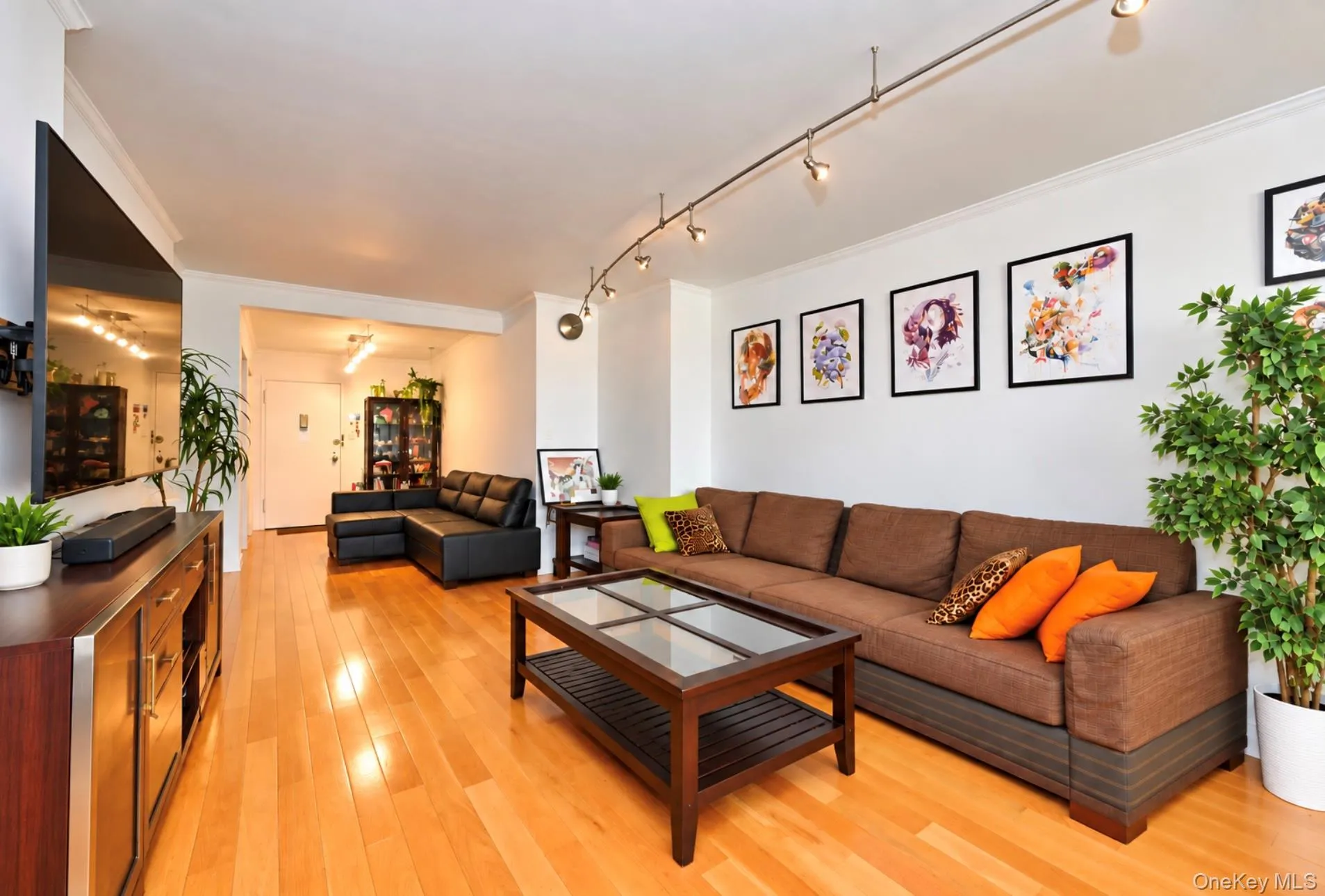 Hardwood-style flooring, white walls with crown molding, track lighting, and a built-in media console Hardwood-style flooring, white walls with crown molding, track lighting, and a built-in media console