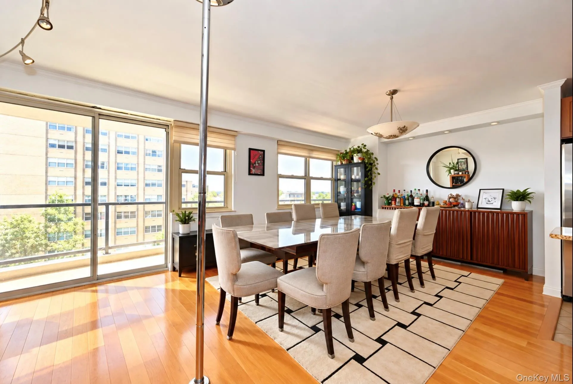 Hardwood flooring, sliding glass door access to a balcony, multiple windows with neutral blinds, recessed lighting, and a decorative ceiling fixture Hardwood flooring, sliding glass door access to a balcony, multiple windows with neutral blinds, recessed lighting, and a decorative ceiling fixture