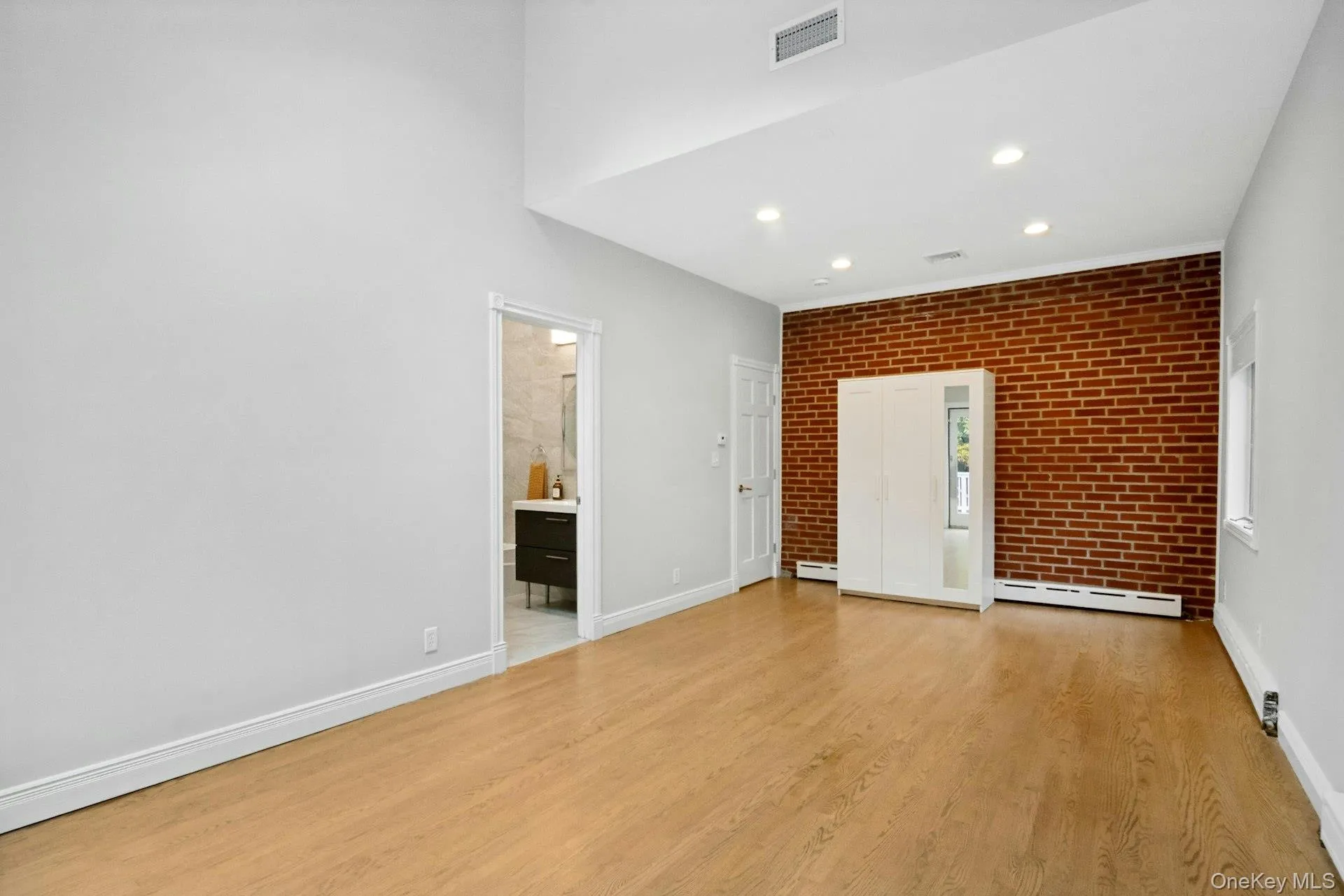 Primary bedroom with brick accent wall. Primary bedroom with brick accent wall.