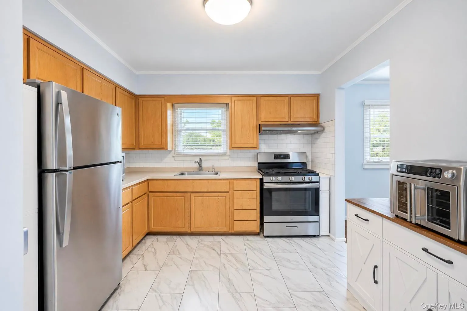 Light wood cabinetry with stainless steel appliances, white subway tile backsplash, and light-toned tile flooring Light wood cabinetry with stainless steel appliances, white subway tile backsplash, and light-toned tile flooring