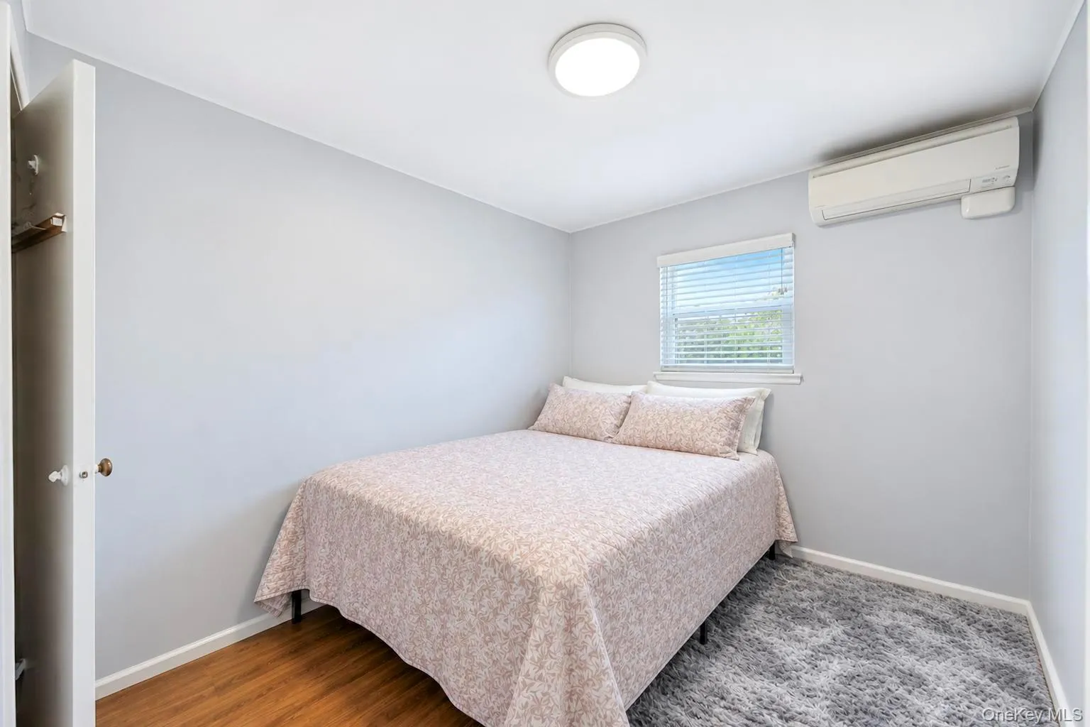 Recessed lighting, wood-finish flooring, built-in air conditioning unit, window with blinds, and painted walls Recessed lighting, wood-finish flooring, built-in air conditioning unit, window with blinds, and painted walls