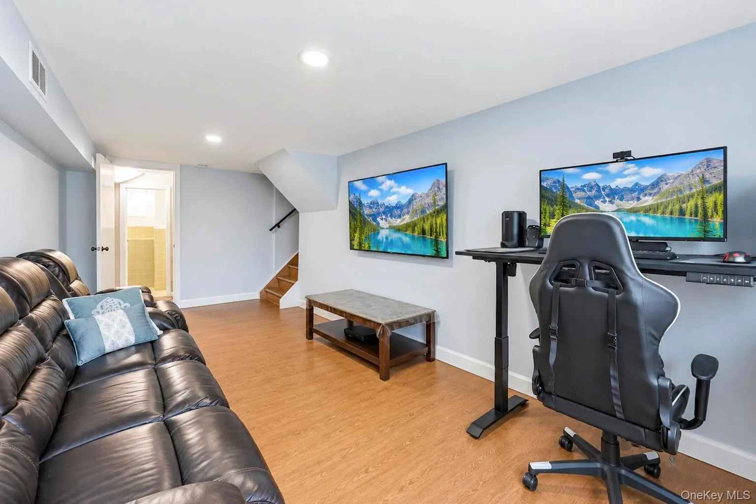Wood-finish flooring throughout, recessed lighting, and a visible staircase Wood-finish flooring throughout, recessed lighting, and a visible staircase