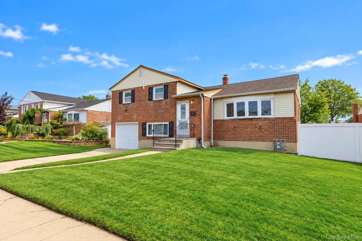 Brick exterior with contrasting siding, attached garage, and a lush front lawn Brick exterior with contrasting siding, attached garage, and a lush front lawn