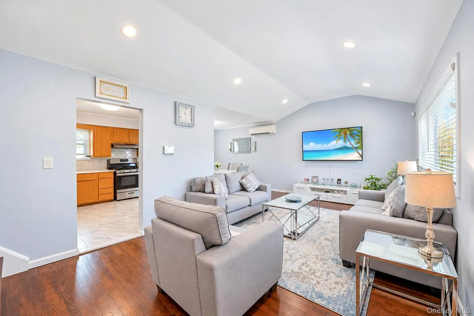 Vaulted ceiling with recessed lighting, wood-finish flooring, wall-mounted air conditioning unit, kitchen with wood cabinetry, and stainless steel range with hood Vaulted ceiling with recessed lighting, wood-finish flooring, wall-mounted air conditioning unit, kitchen with wood cabinetry, and stainless steel range with hood