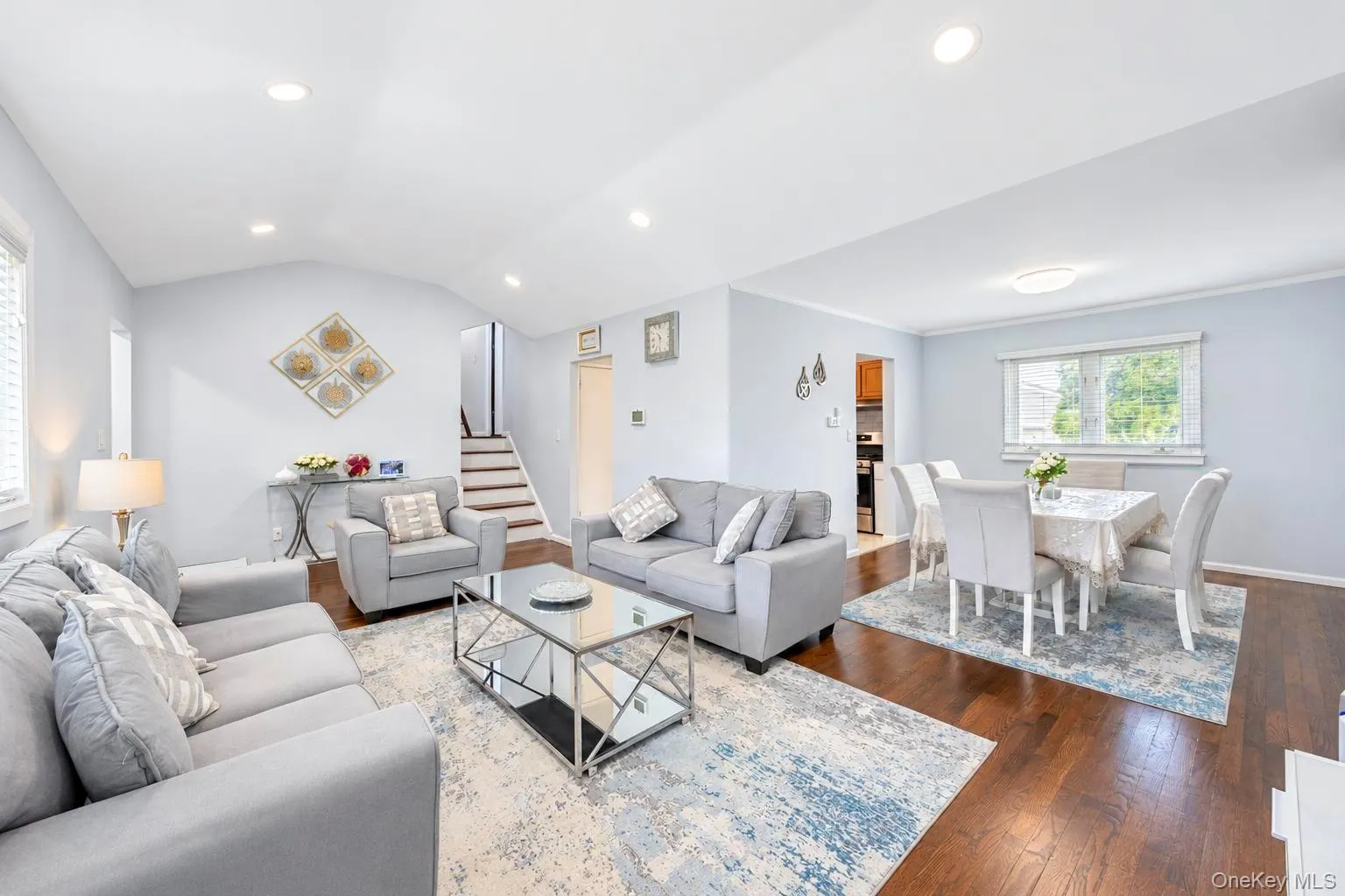Open-concept living and dining area featuring wood-finish flooring, recessed lighting, and a vaulted ceiling Open-concept living and dining area featuring wood-finish flooring, recessed lighting, and a vaulted ceiling