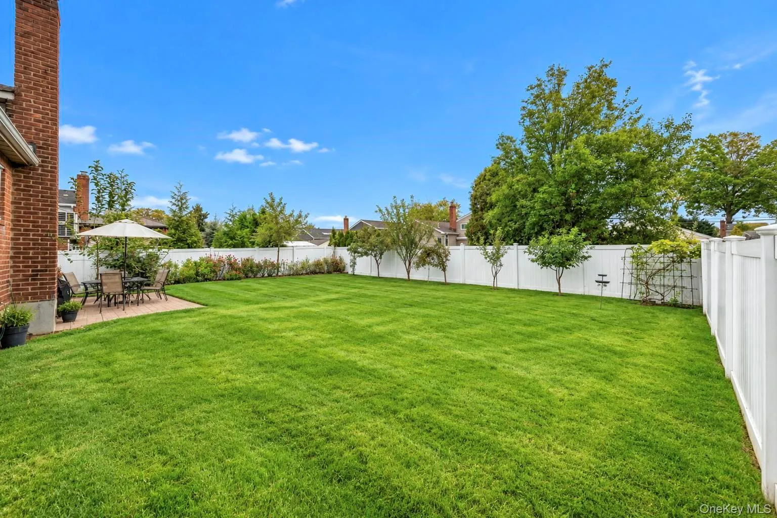 Expansive green lawn, brick exterior, white privacy fencing, paved patio, and established perimeter landscaping Expansive green lawn, brick exterior, white privacy fencing, paved patio, and established perimeter landscaping