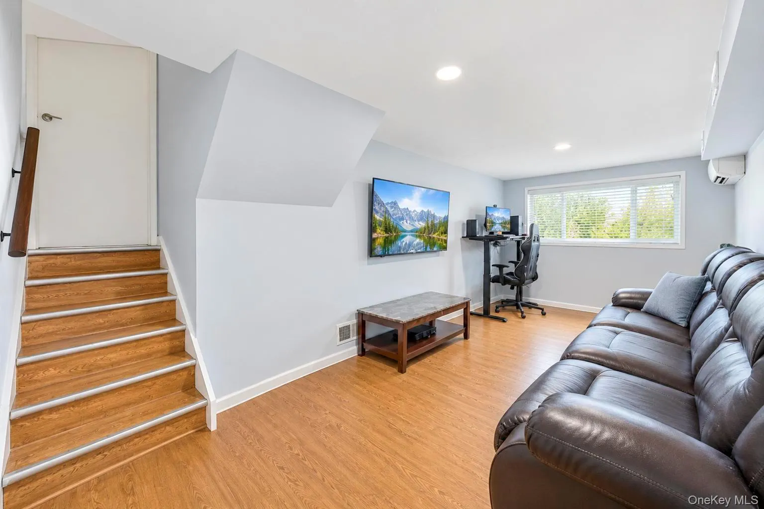 Wood-finish flooring throughout, recessed lighting, and a large window with white blinds Wood-finish flooring throughout, recessed lighting, and a large window with white blinds