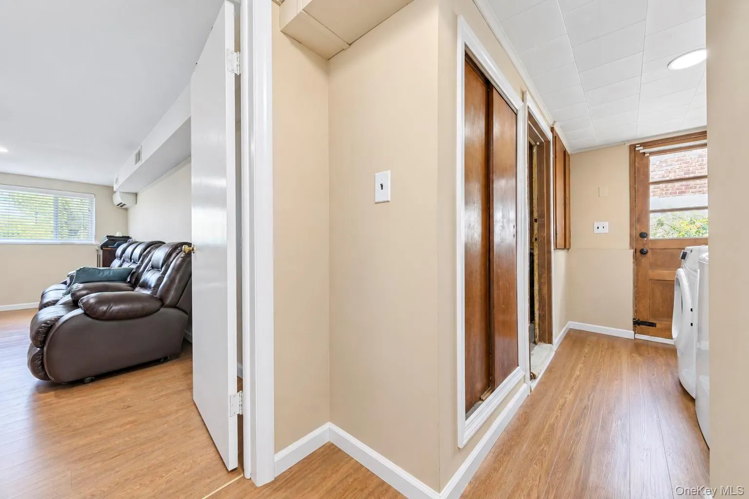 Wood-finish flooring throughout, with a window providing natural light, and a built-in wooden door Wood-finish flooring throughout, with a window providing natural light, and a built-in wooden door