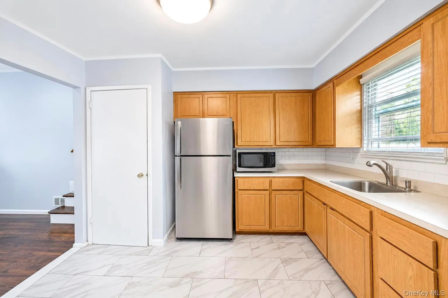 Kitchen featuring wood cabinetry, white countertops, tile flooring, and a stainless steel refrigerator Kitchen featuring wood cabinetry, white countertops, tile flooring, and a stainless steel refrigerator