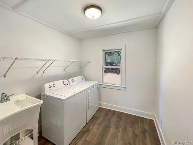 Laundry room featuring wood-finish flooring, white walls, built-in wire shelving, and a utility sink Laundry room featuring wood-finish flooring, white walls, built-in wire shelving, and a utility sink